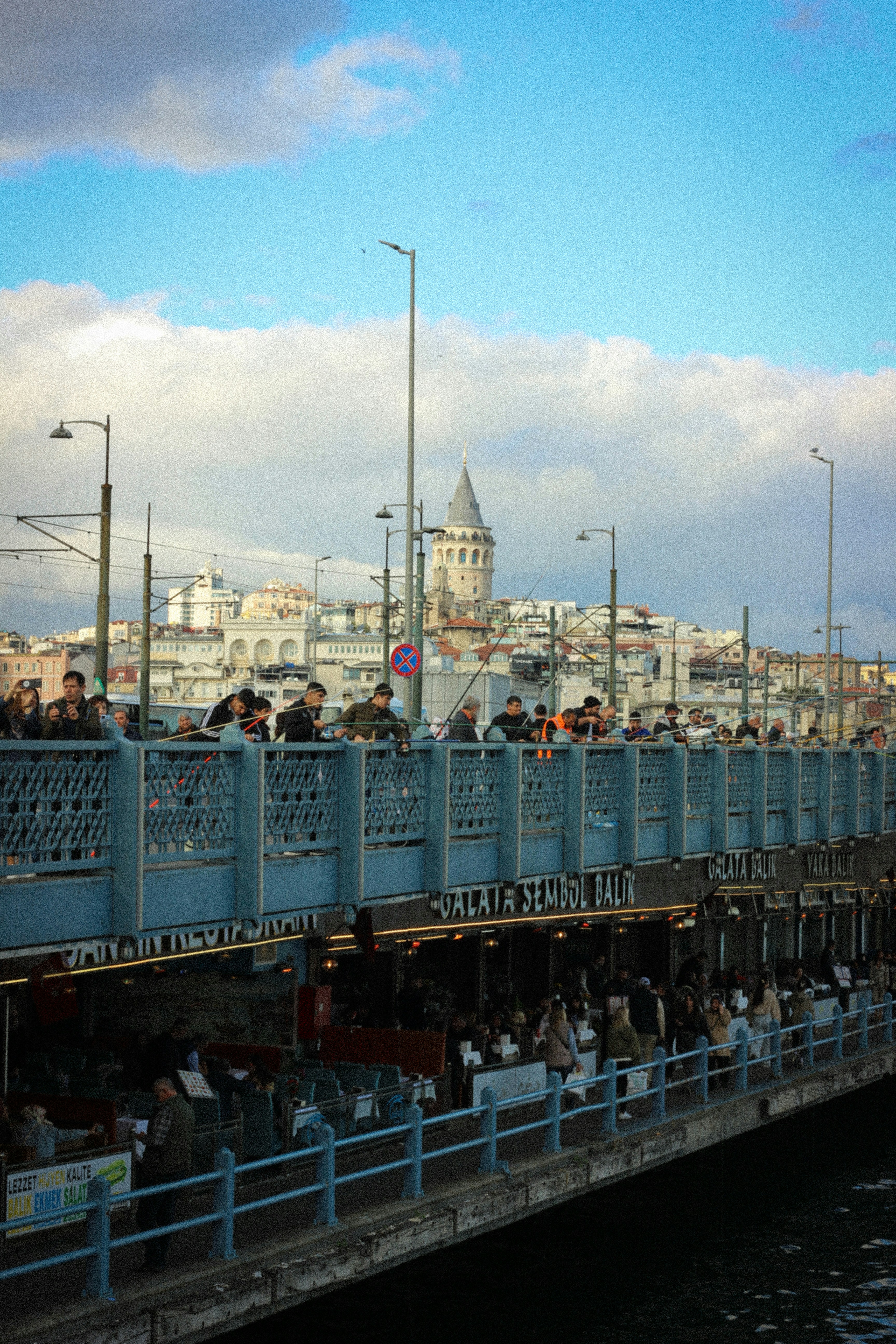 People gather on a bridge with buildings in the background.