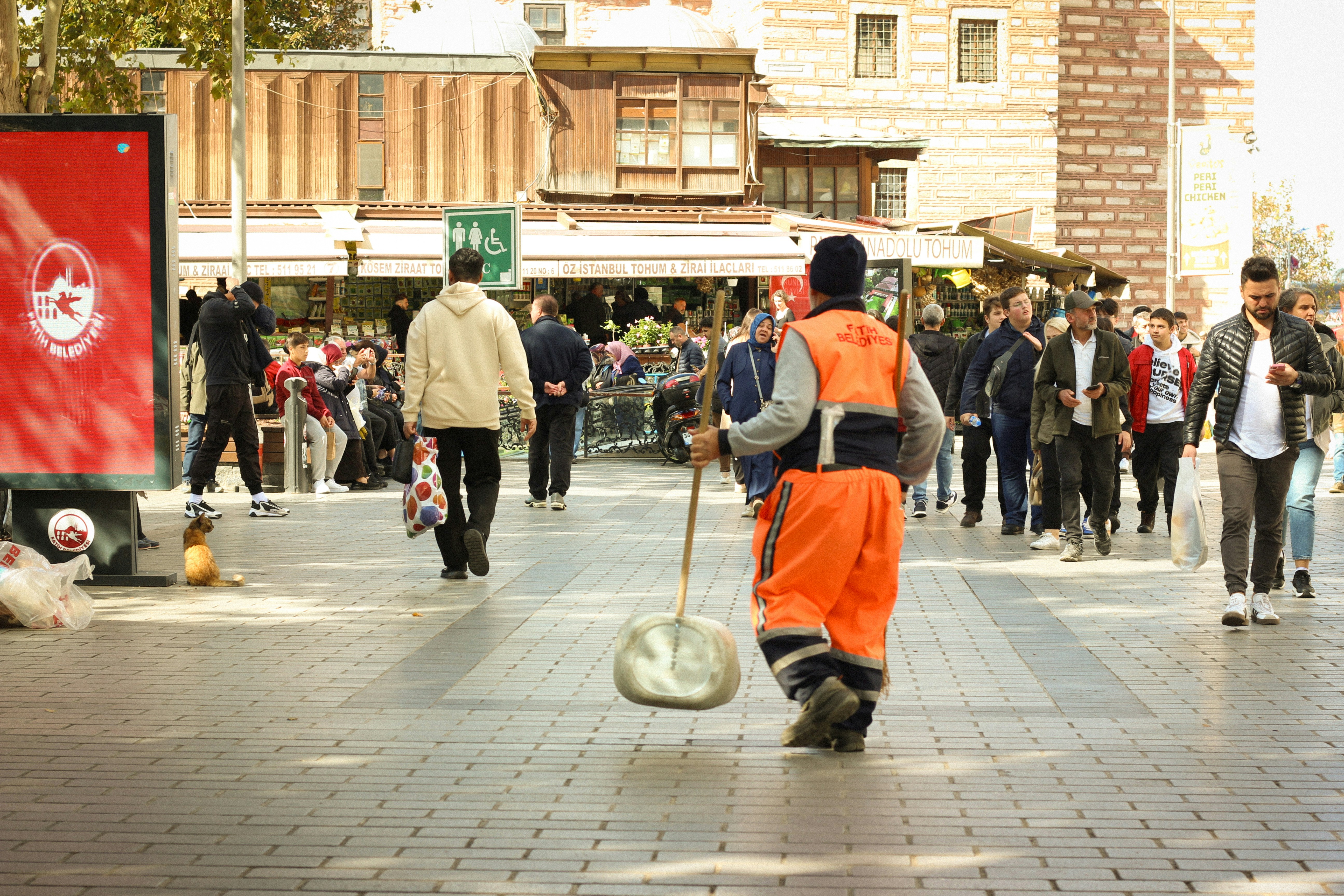 A street sweeper works amidst bustling city life.