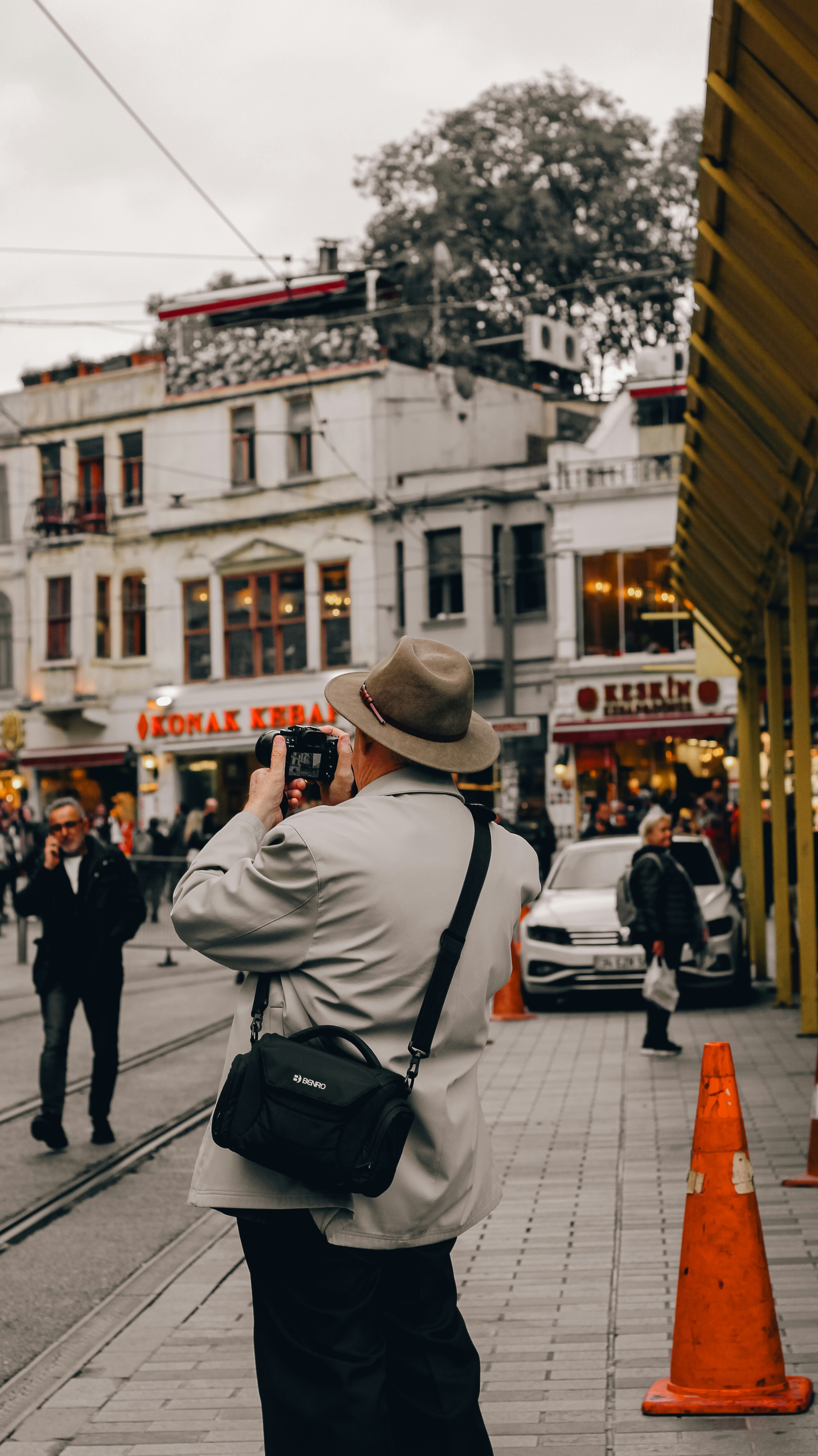 Photographe avec un chapeau prenant des photos dans une rue de la ville.