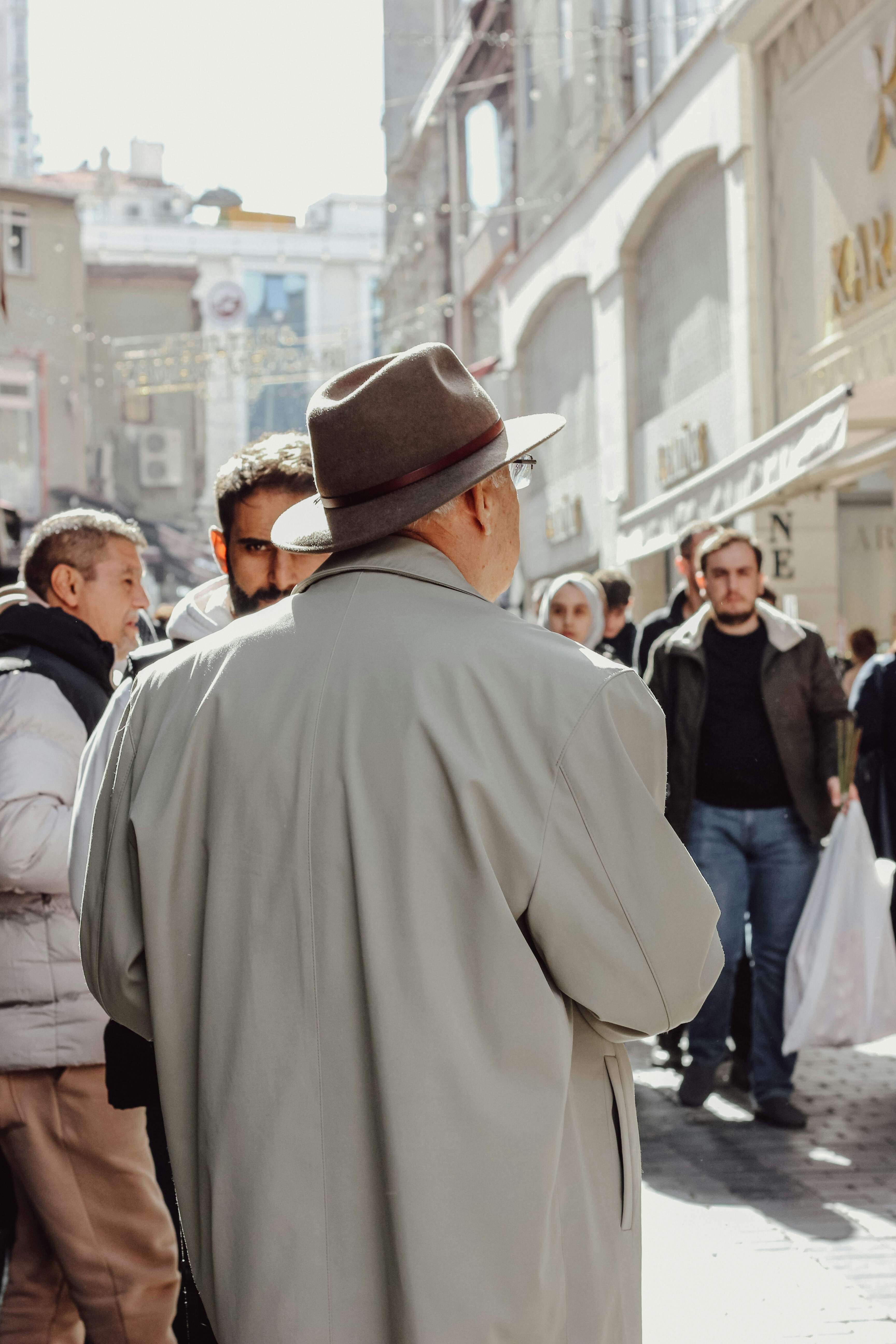Un homme avec un chapeau marche dans une rue animée.