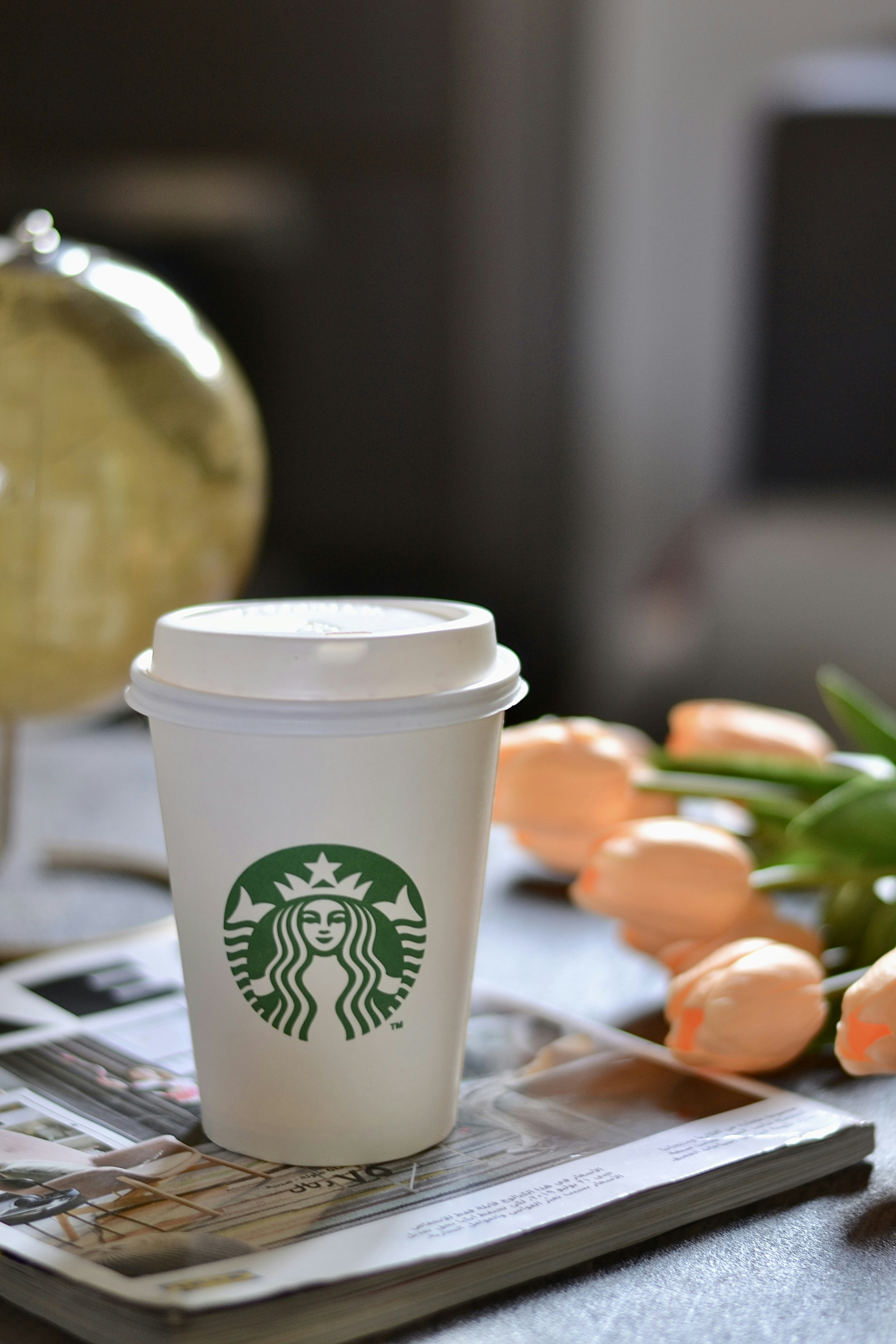 花と地球儀とスターバックスのコーヒーカップ。