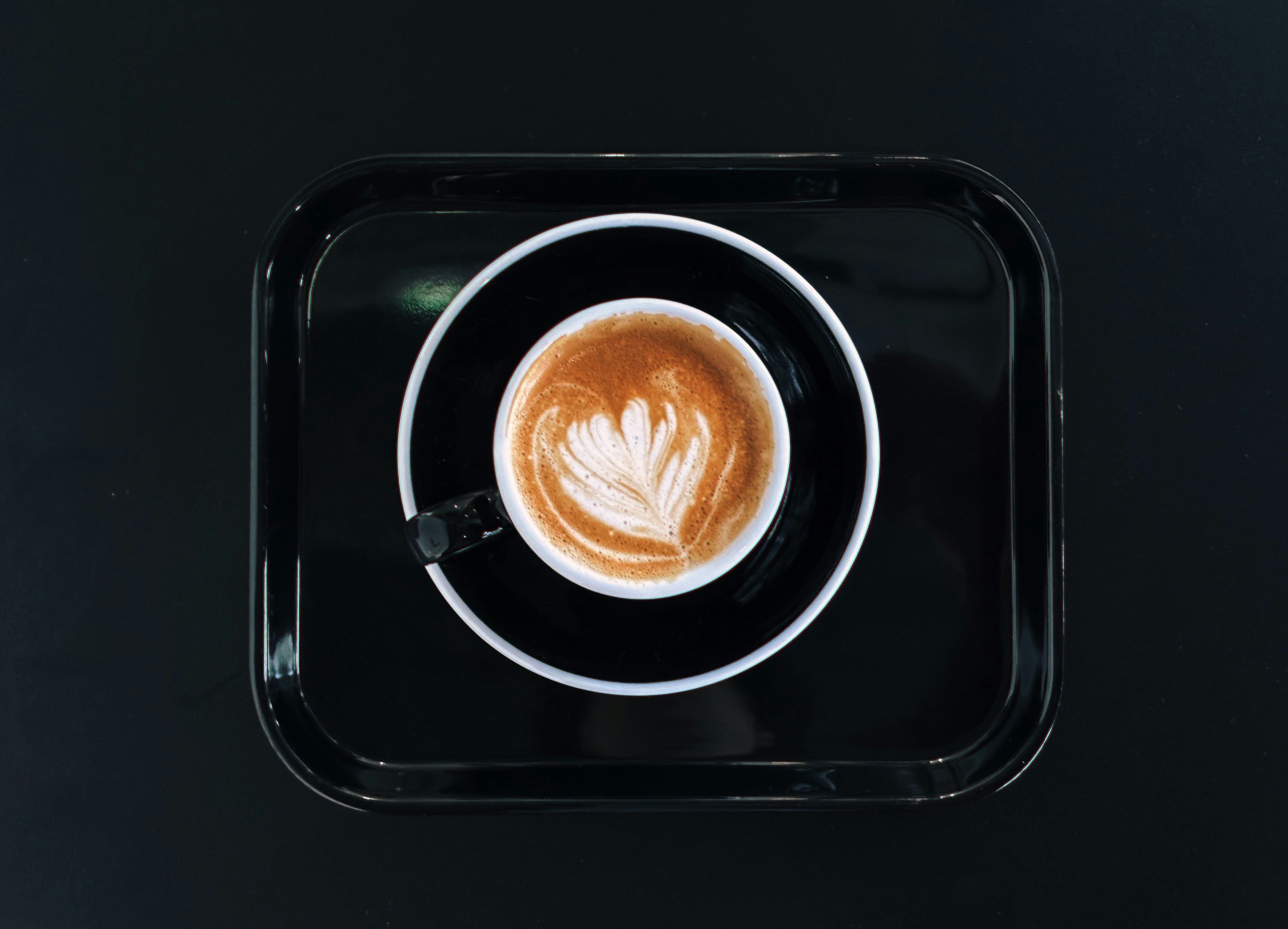 Latte on a black tray from above