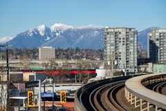 Cityscape with snowy mountains and train tracks.