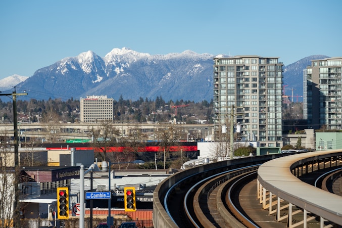 Cityscape with snowy mountains and train tracks.