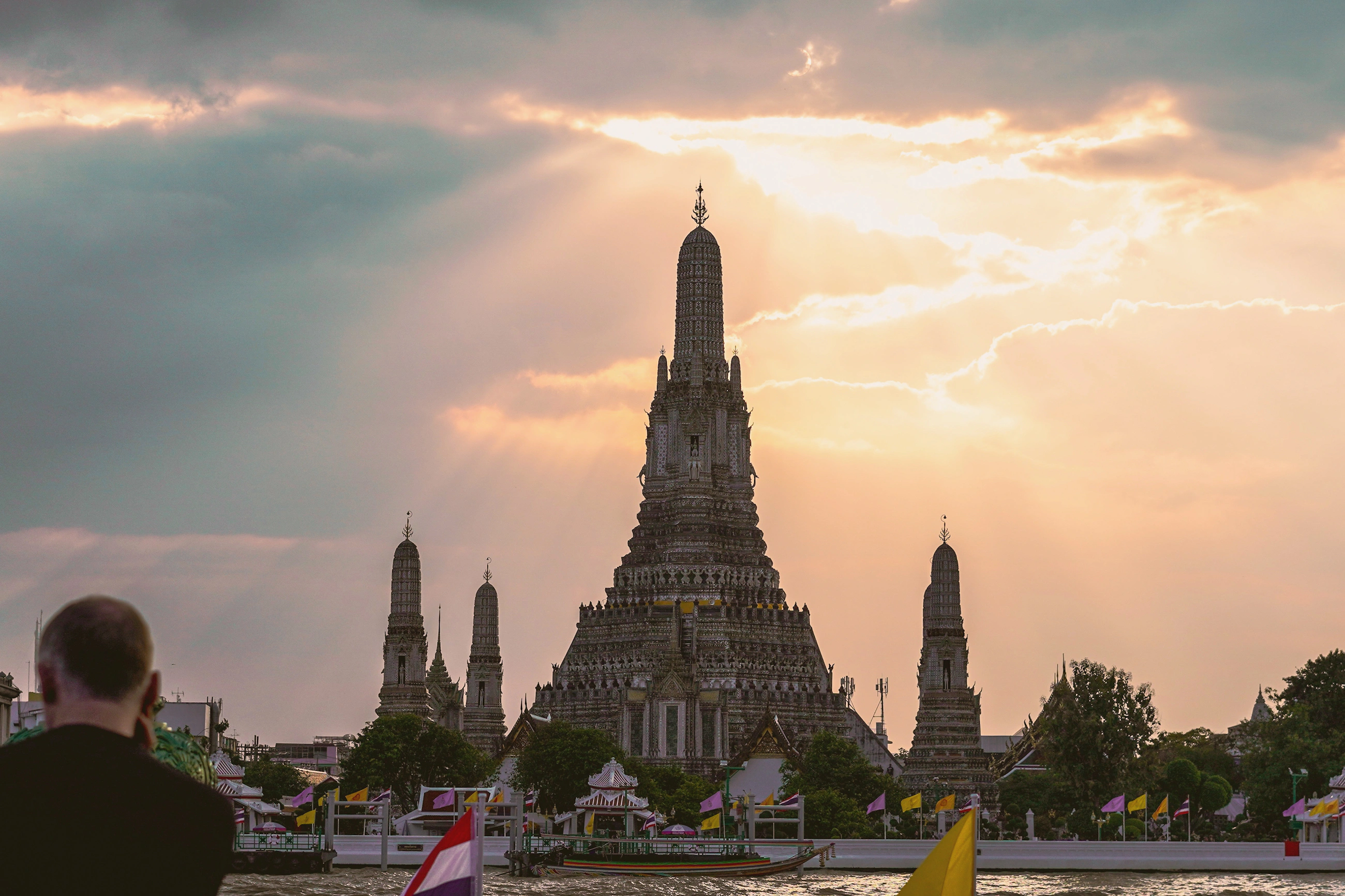 Wat Arun glowing beside the Chao Phraya River at sunset in Bangkok, Thailand