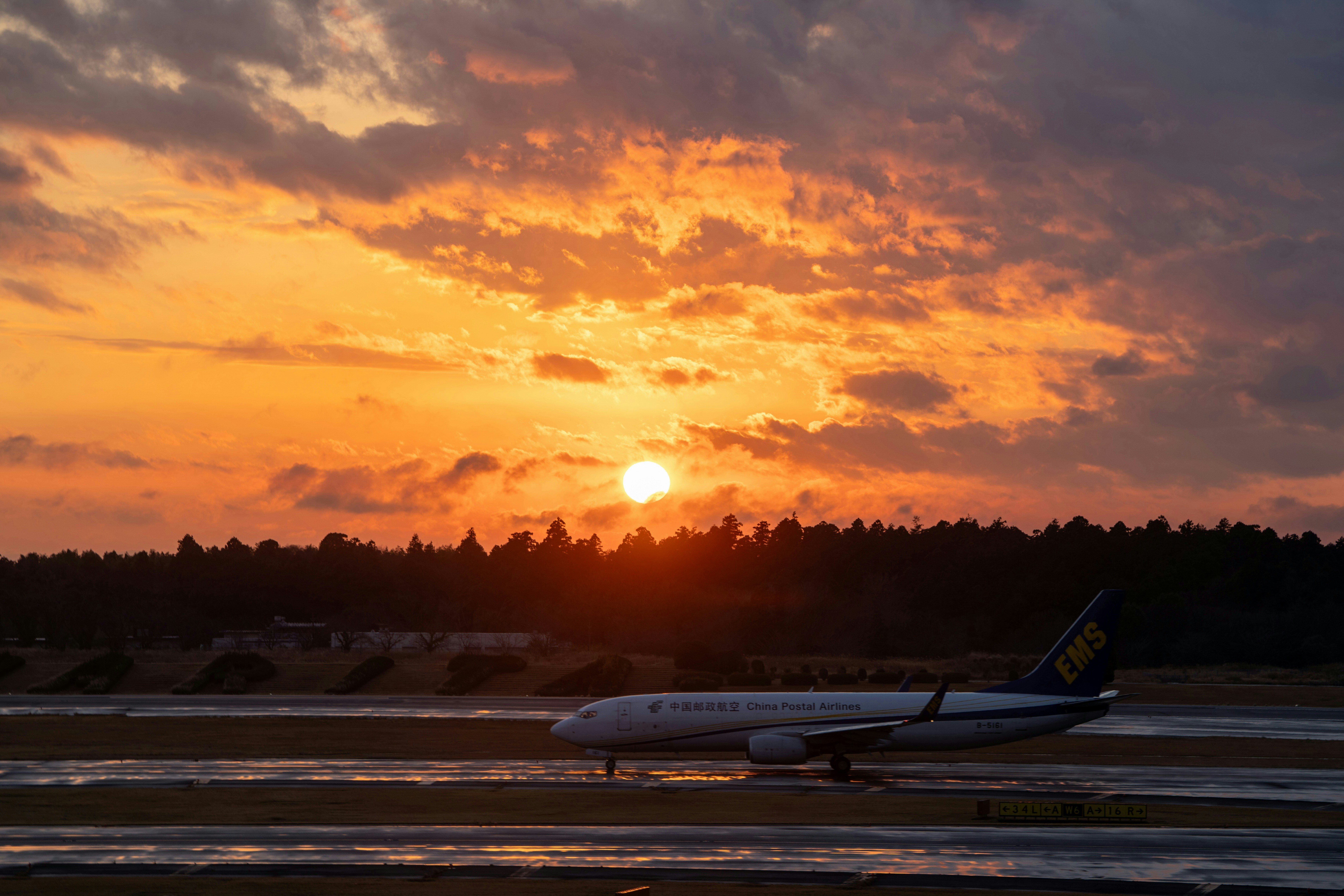 A plane sits on the runway at sunset.