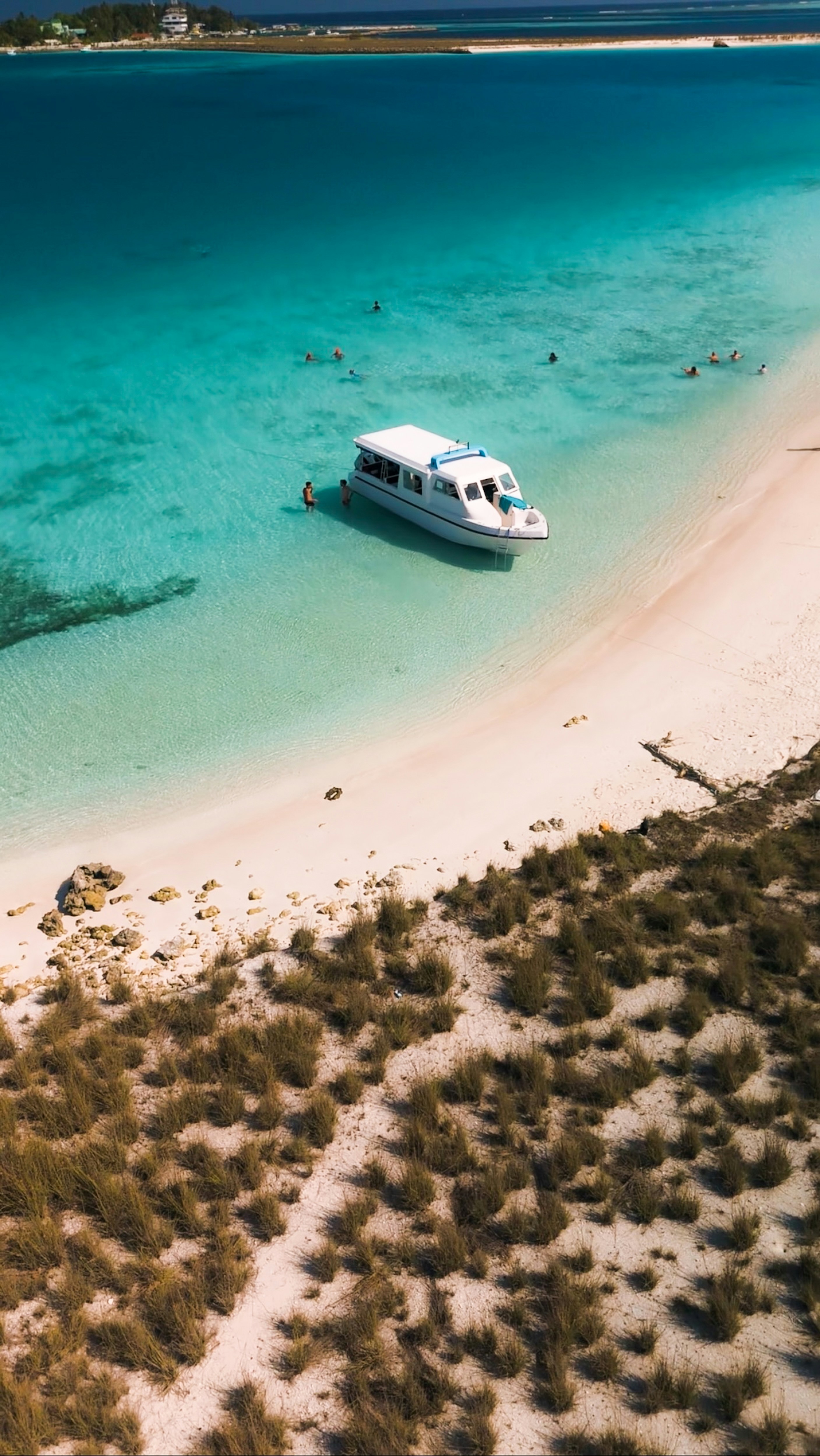 Boat on a beach with clear, turquoise water.