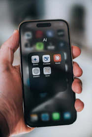 Hand holding a phone with ai application icons.