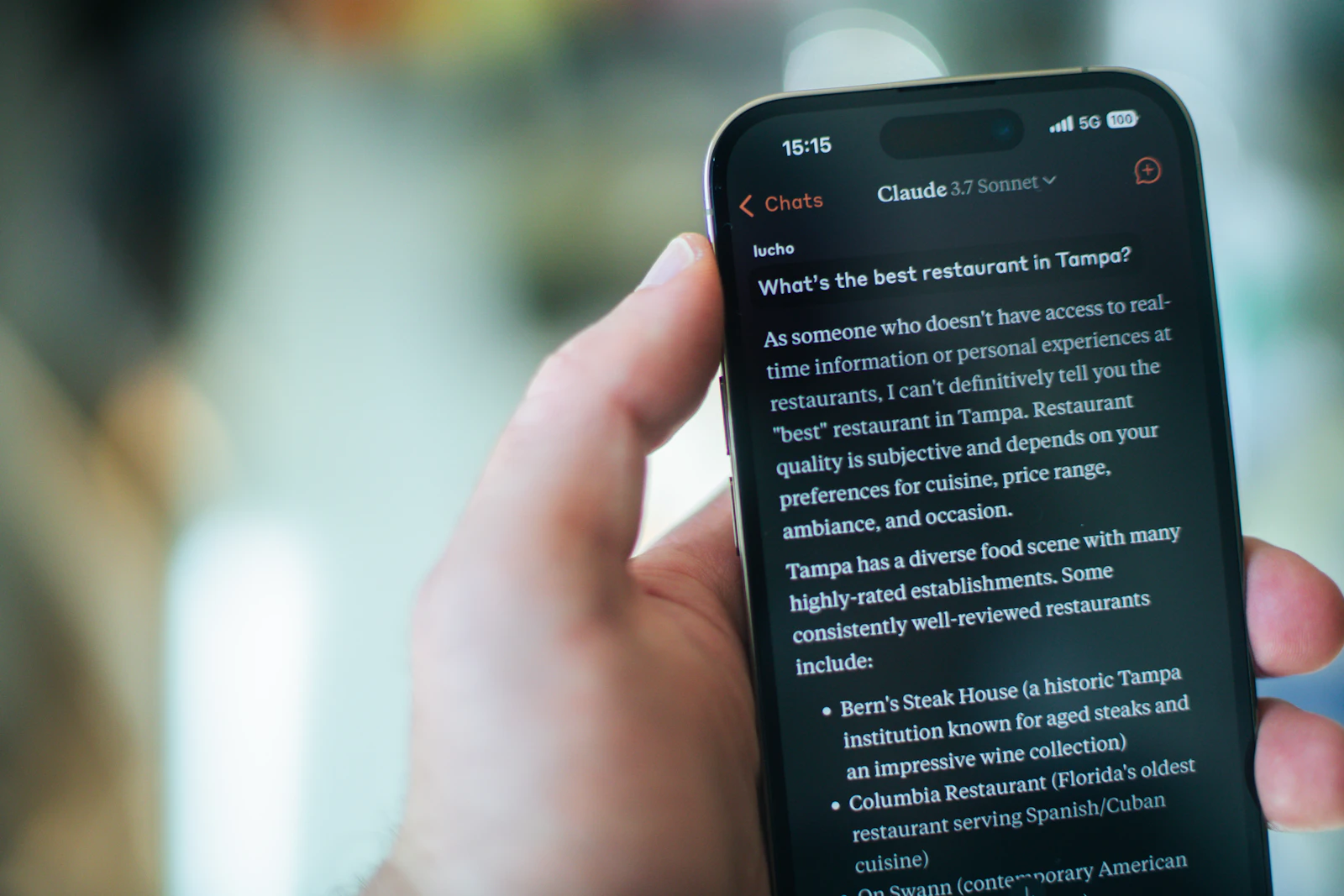 Mano sosteniendo un teléfono con una conversación abierta en la app de Claude