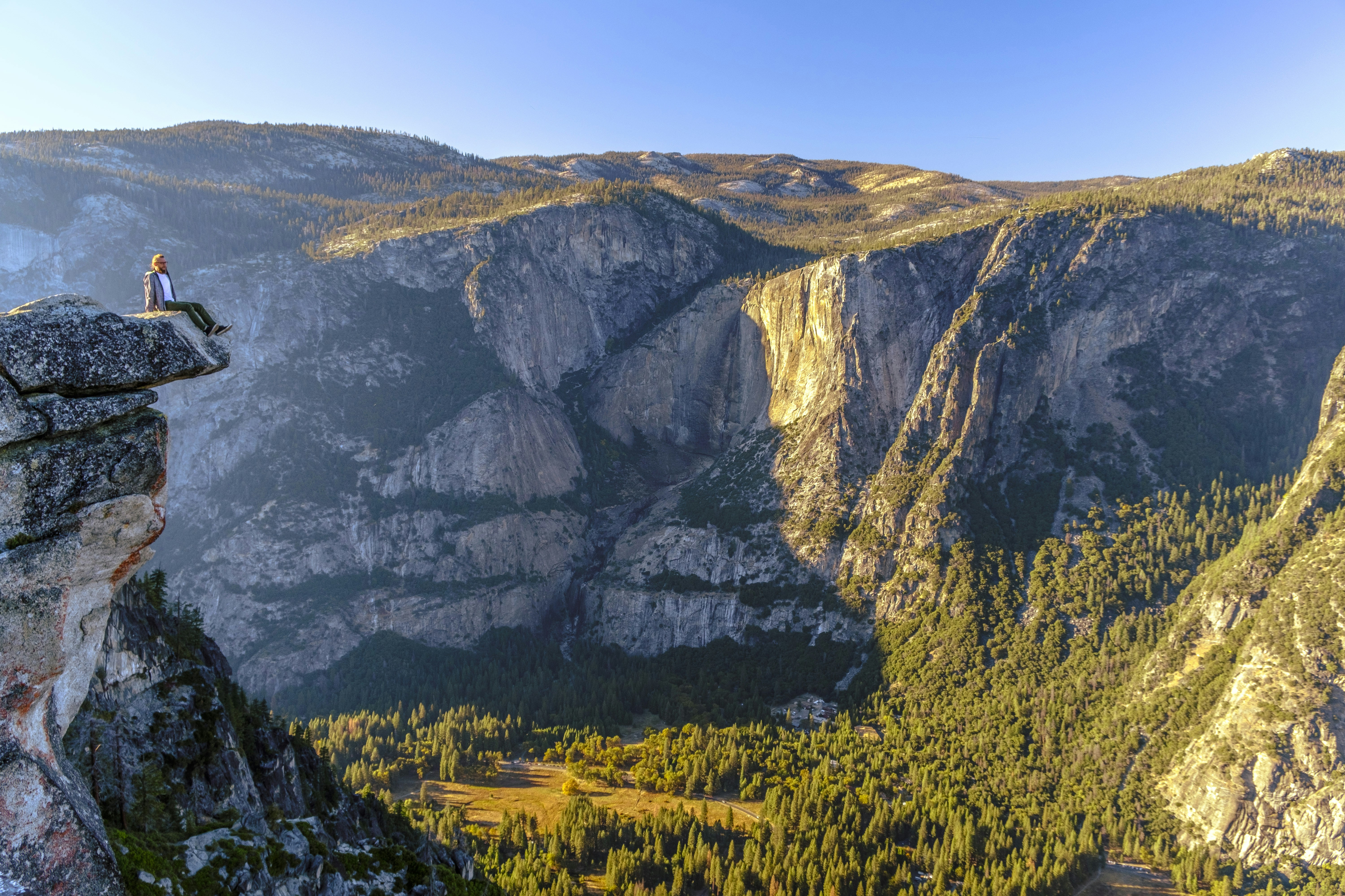 Person sits on the edge, enjoying a mountain view.
