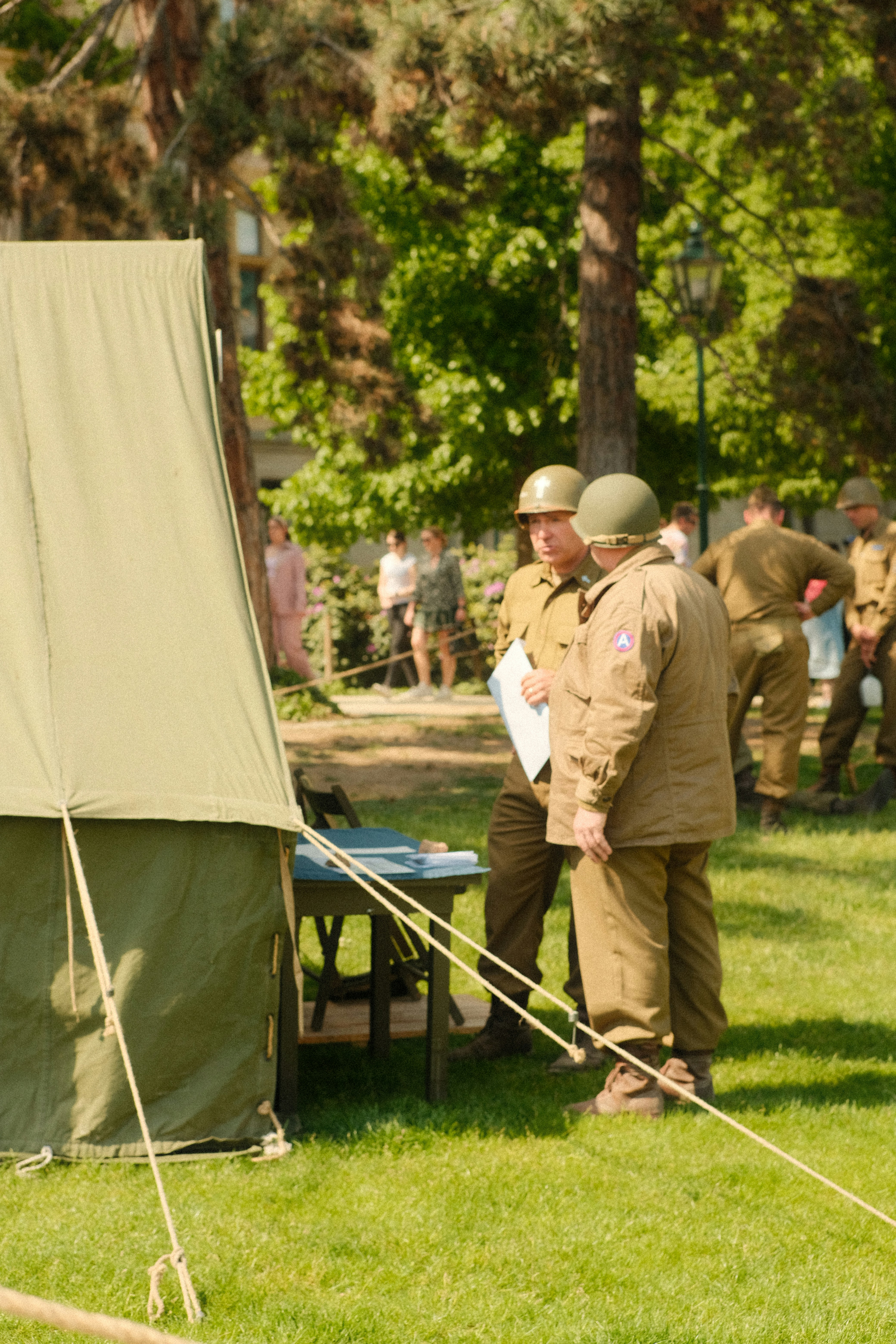 Soldiers in vintage uniforms stand near a tent.