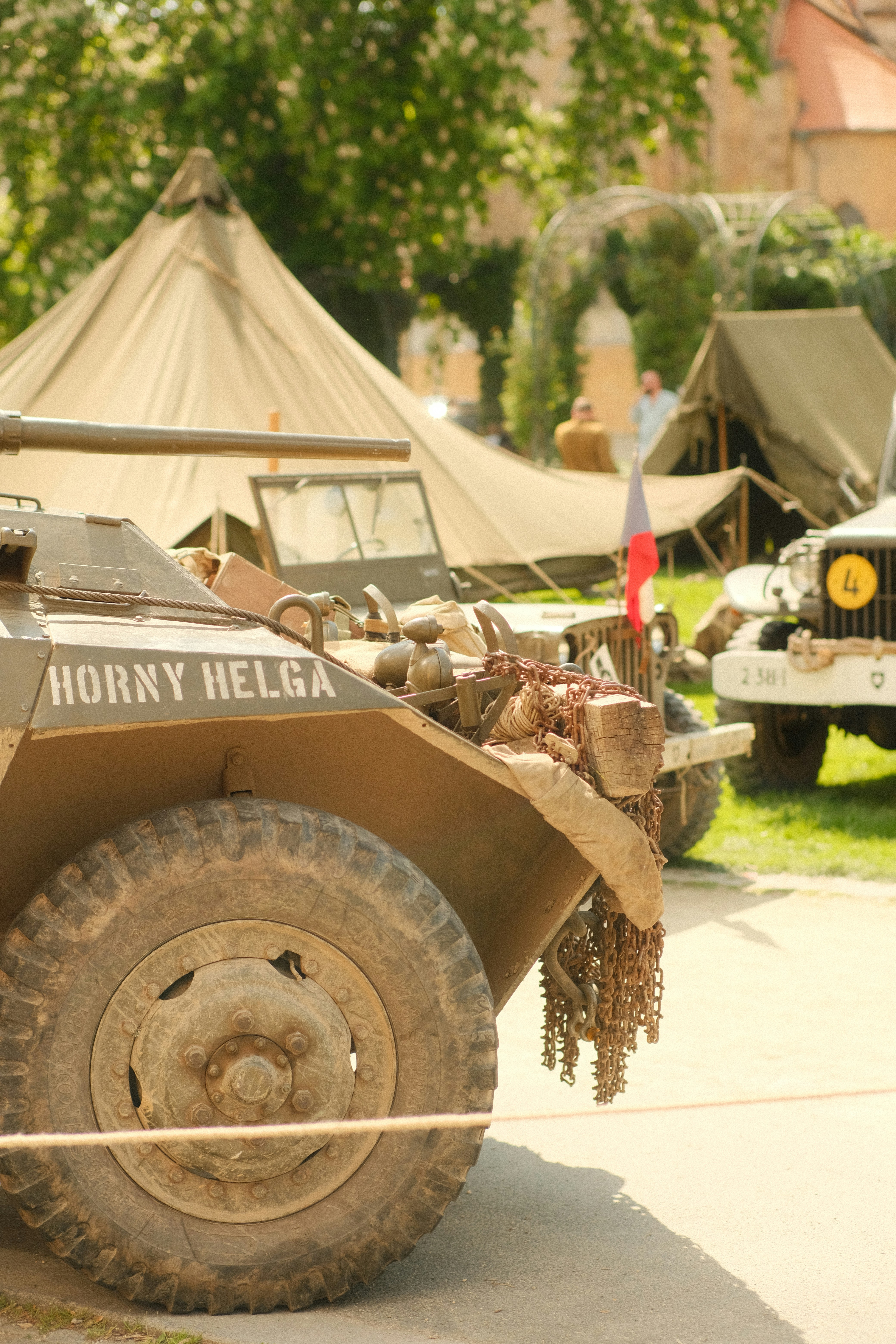 Veículos militares são exibidos perto de tendas.