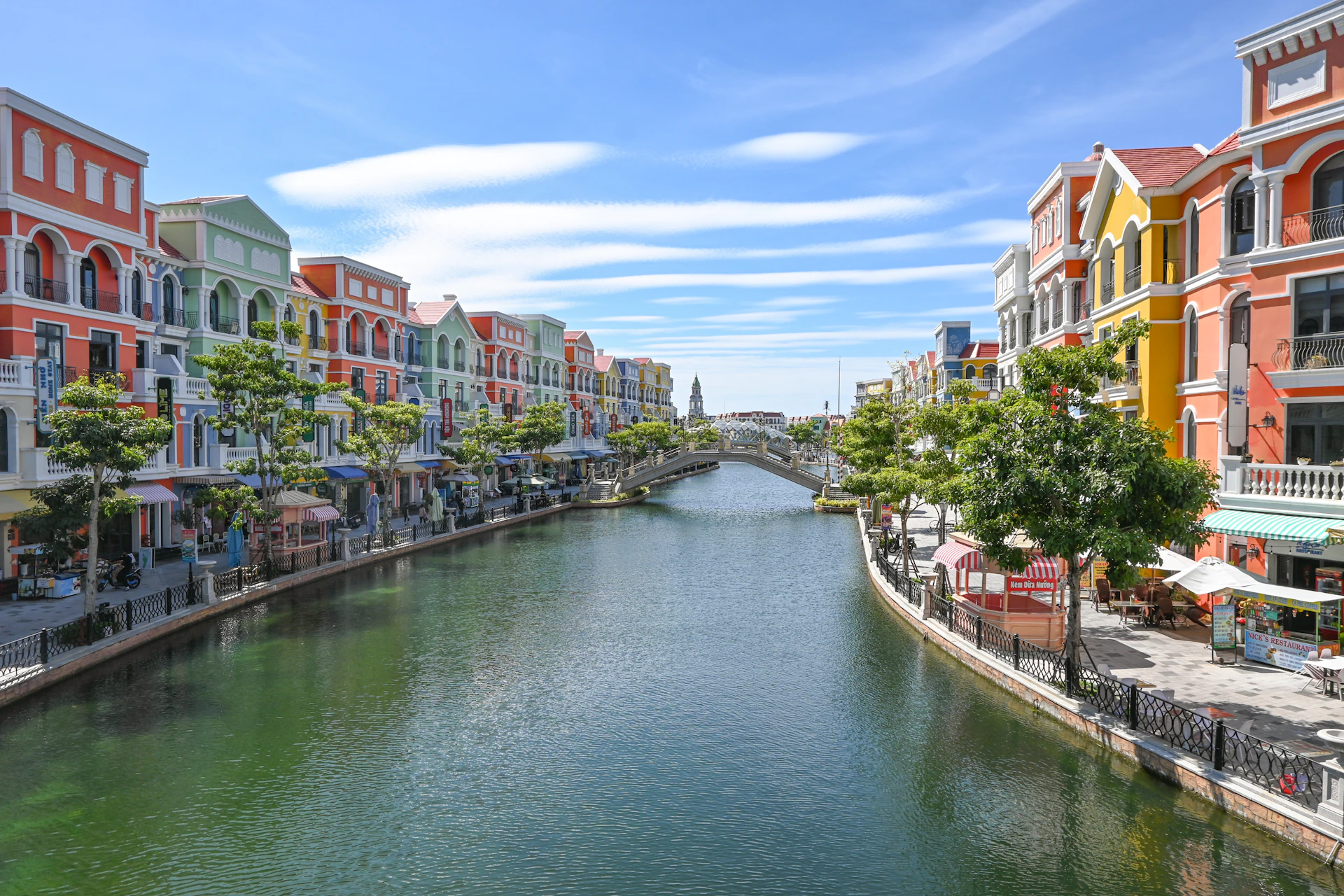 Colorful buildings line a canal with a bridge.