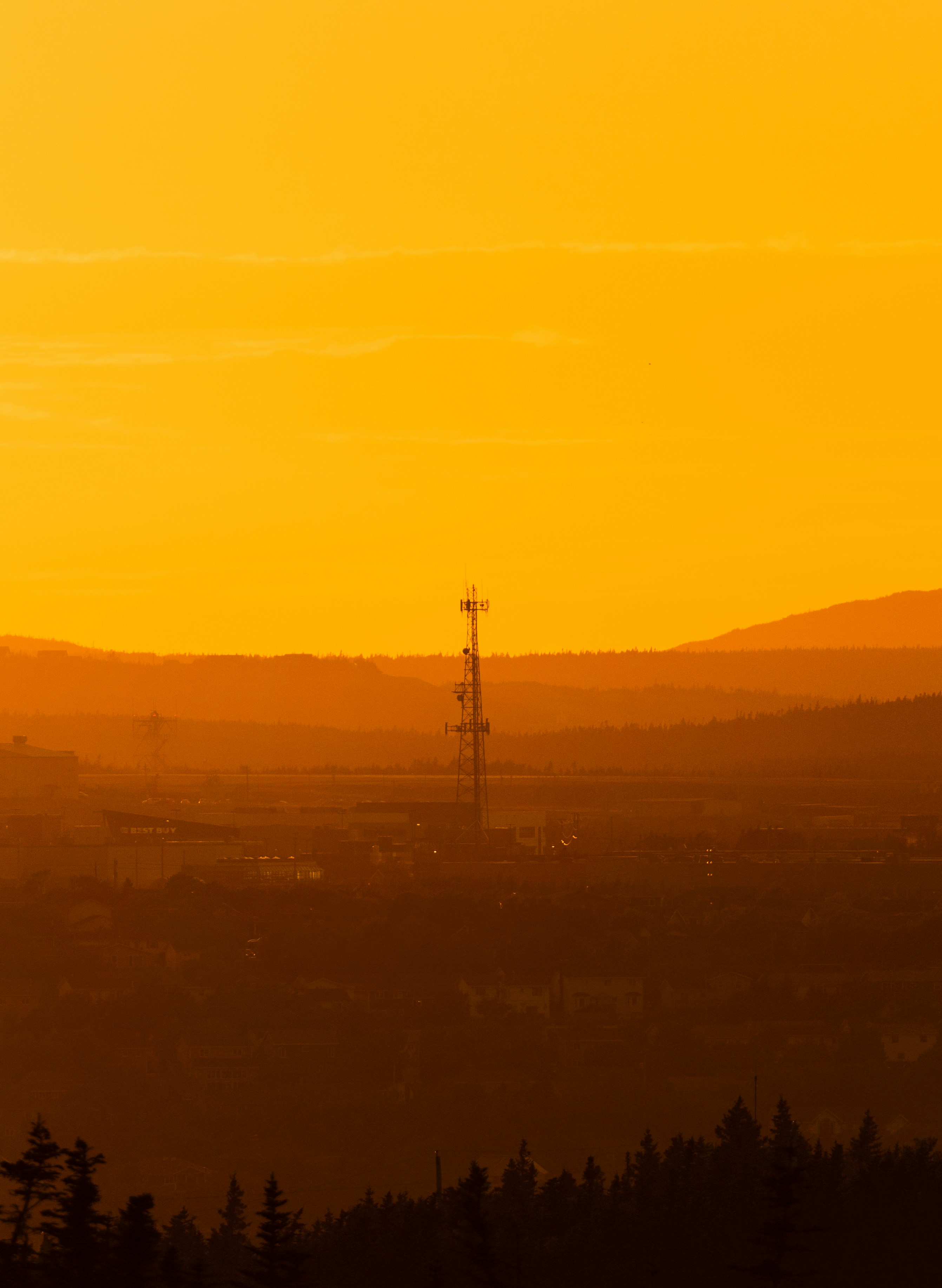 A radio transmission tower silhouetted against a golden sunset.