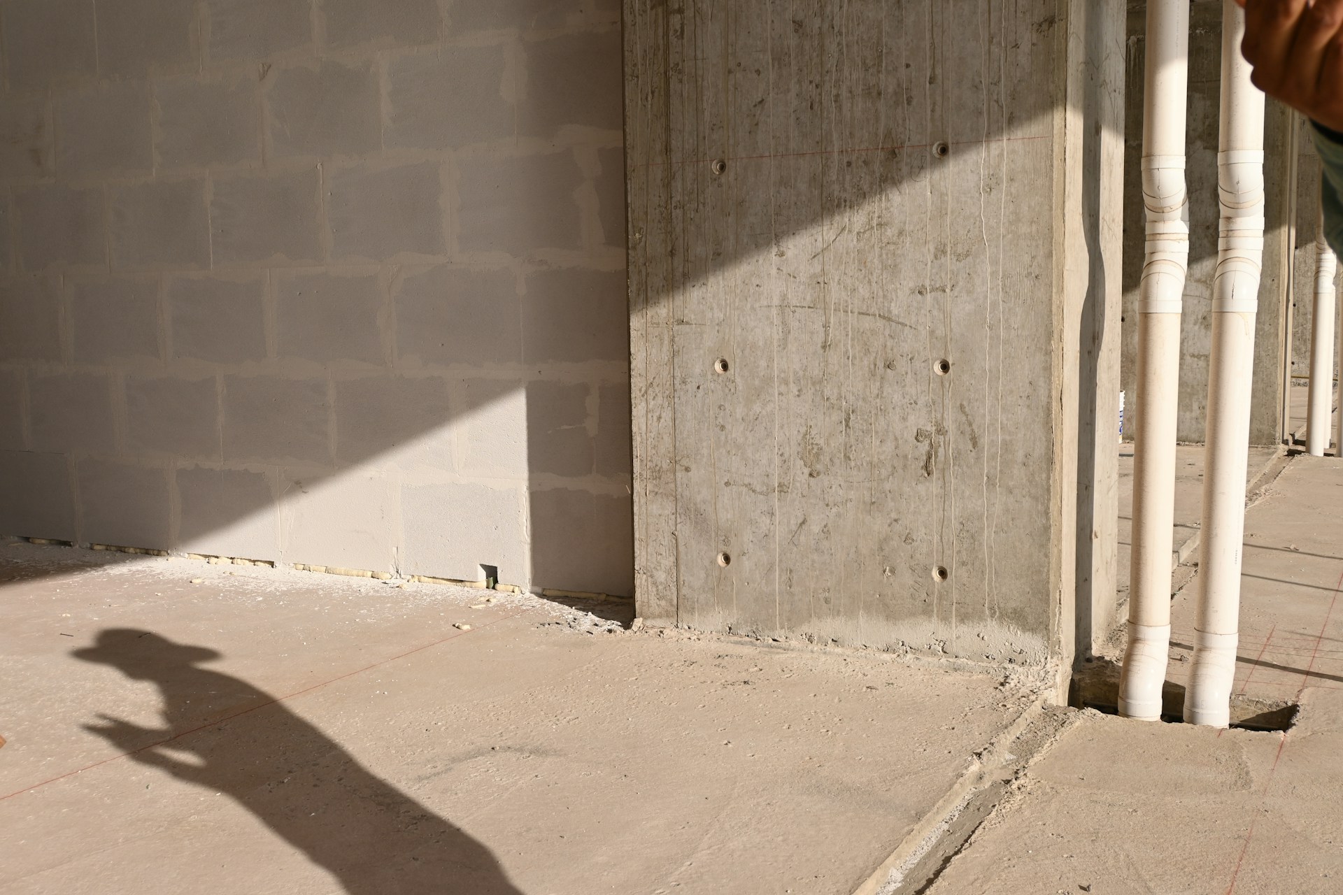 Construction site interior shows walls and pipes.