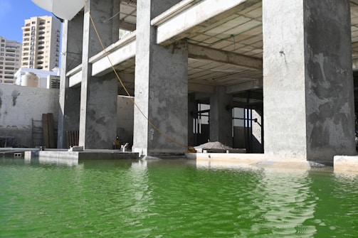 Under-construction building with green water in front.