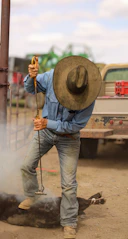 A cowboy brands cattle using a hot iron.