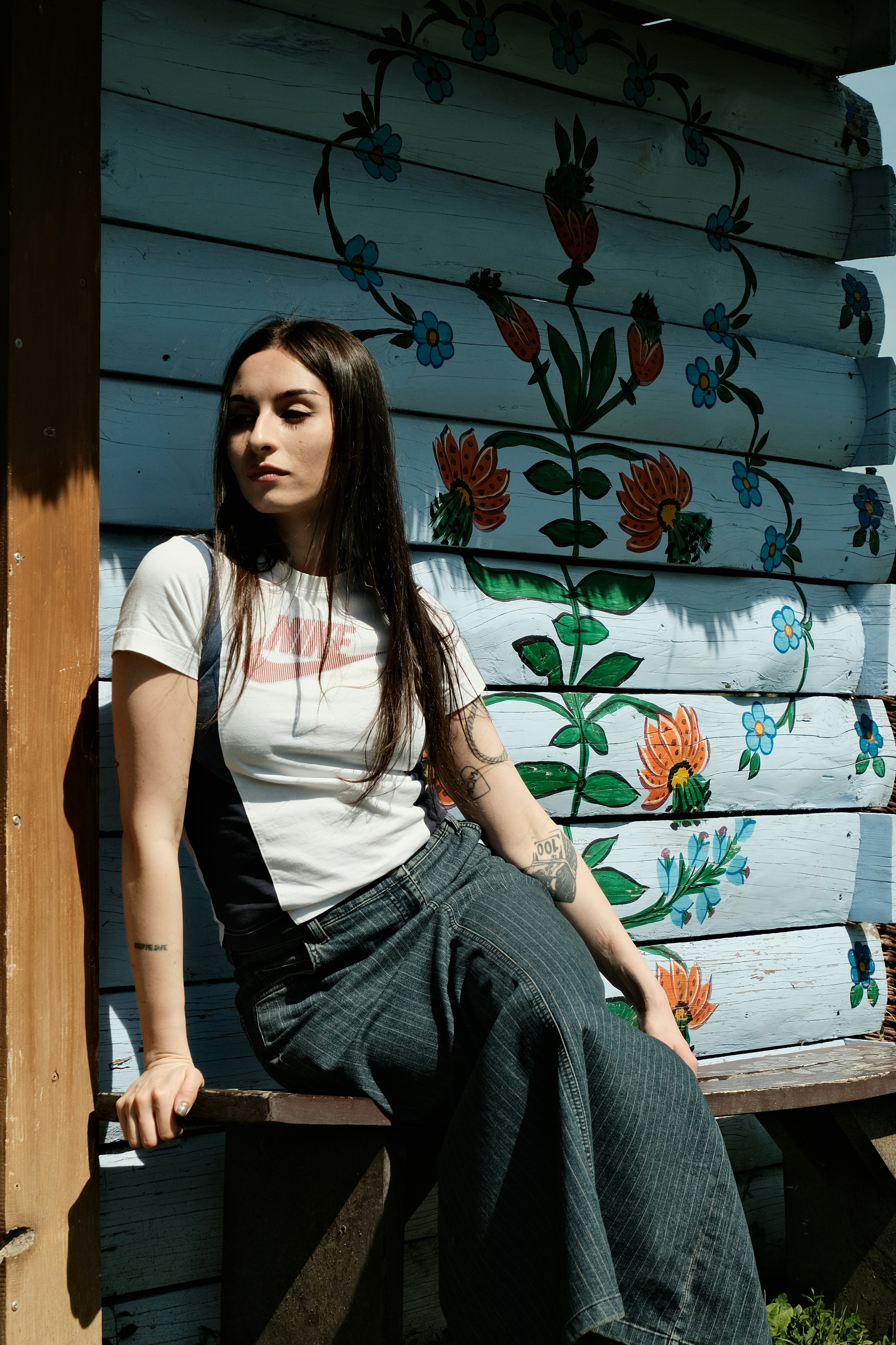Woman poses in front of painted rustic wall.