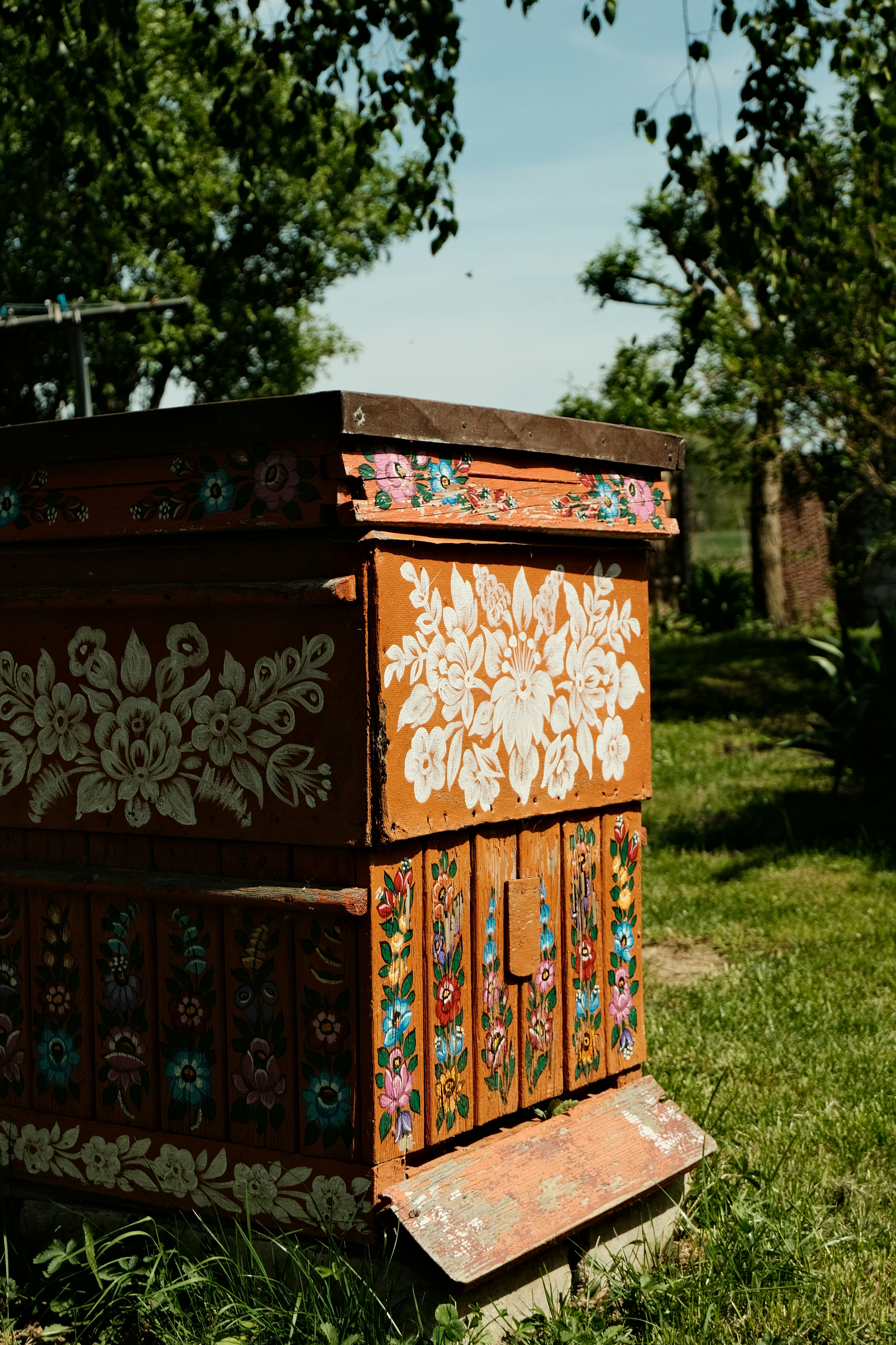 A decorated beehive sits in the lush garden.