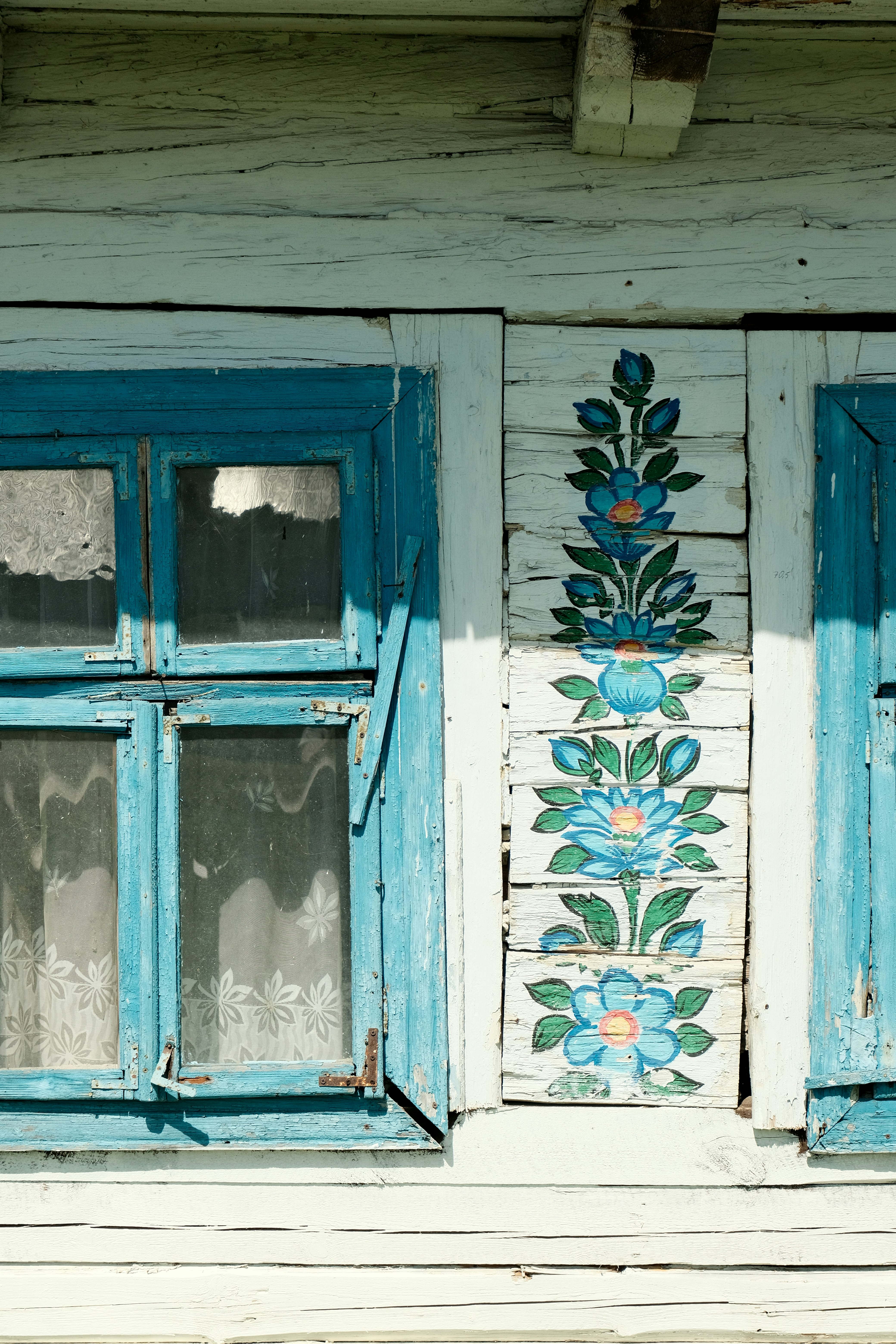 Blue painted floral decor adorns an old window.
