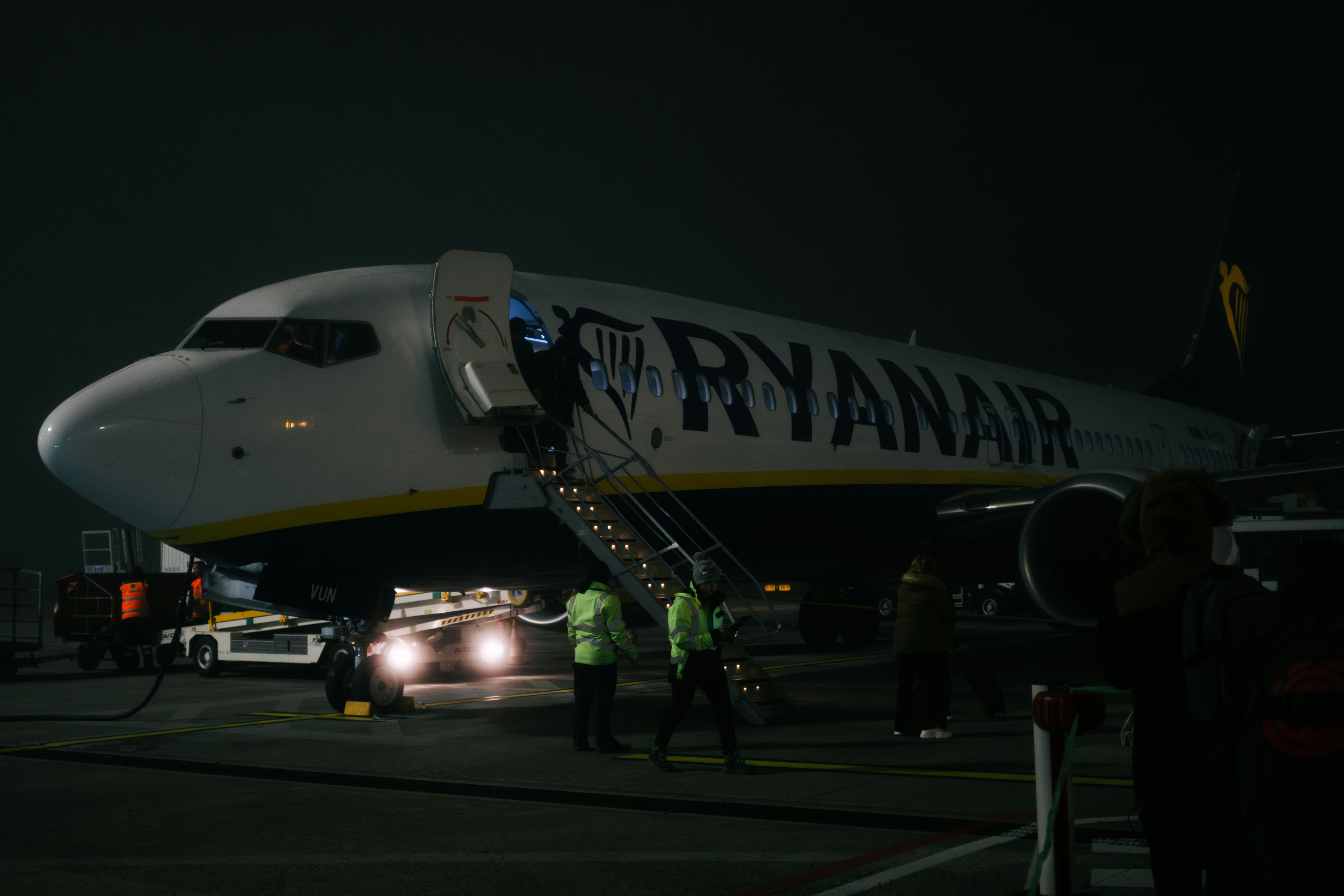 A ryanair plane is boarding passengers at night.