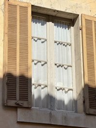 Window with shutters partially open in sunlight.