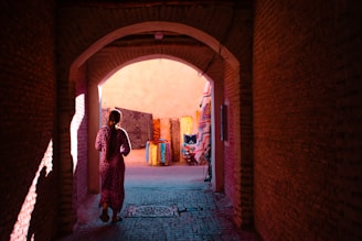 A person walks through an arched passage.