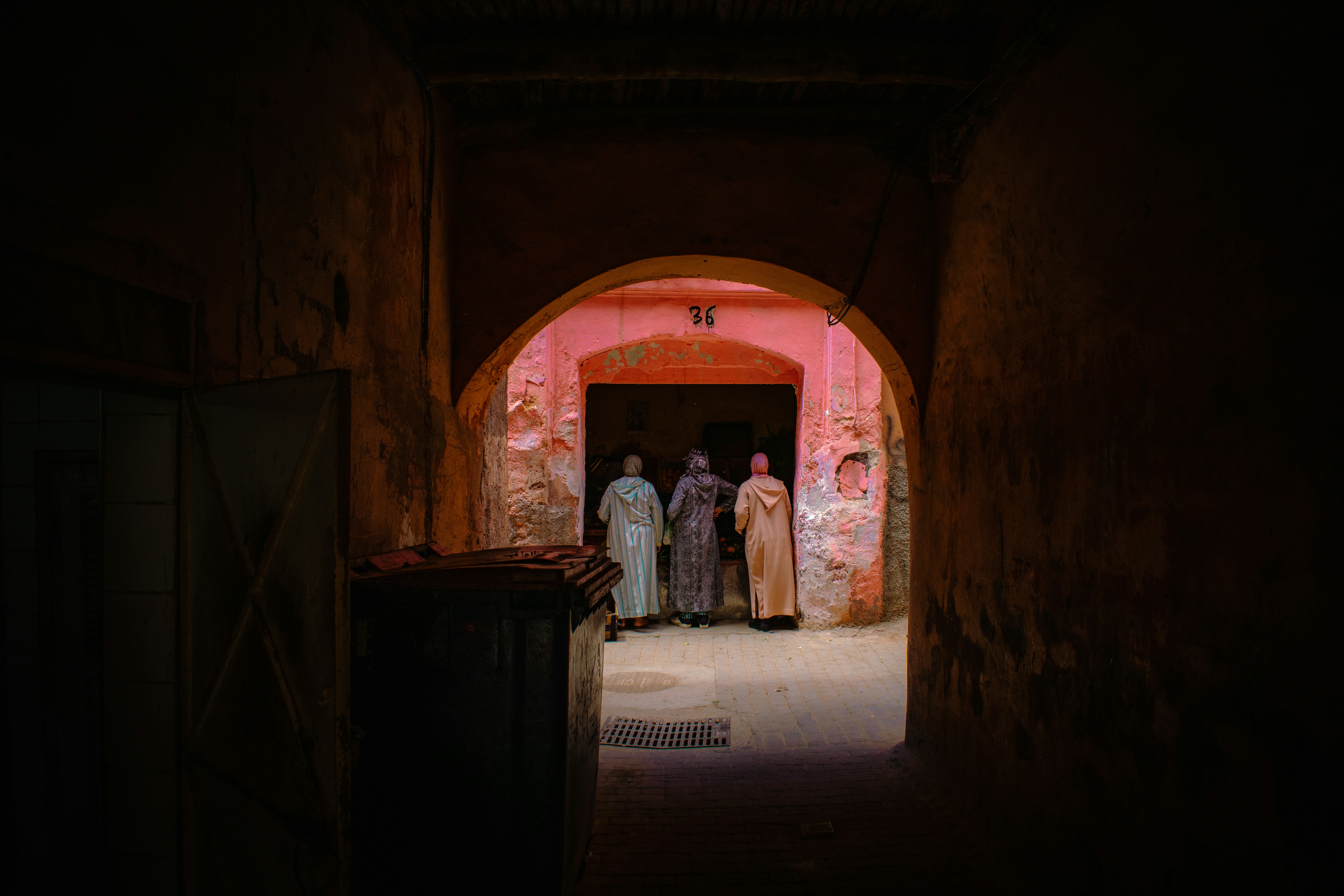 Three figures walk toward a bright, arched doorway.