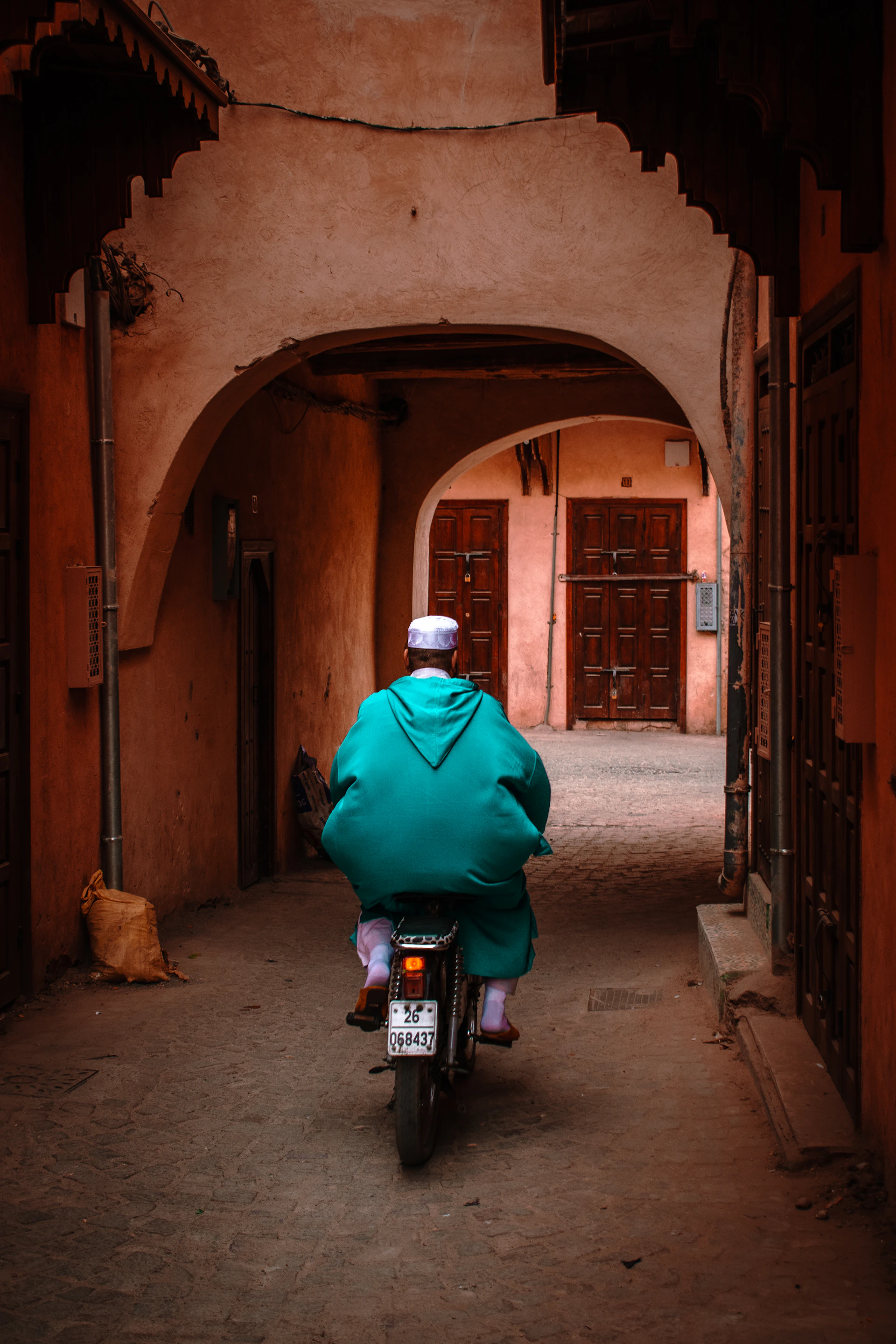 A man rides a motorbike through a narrow alley.