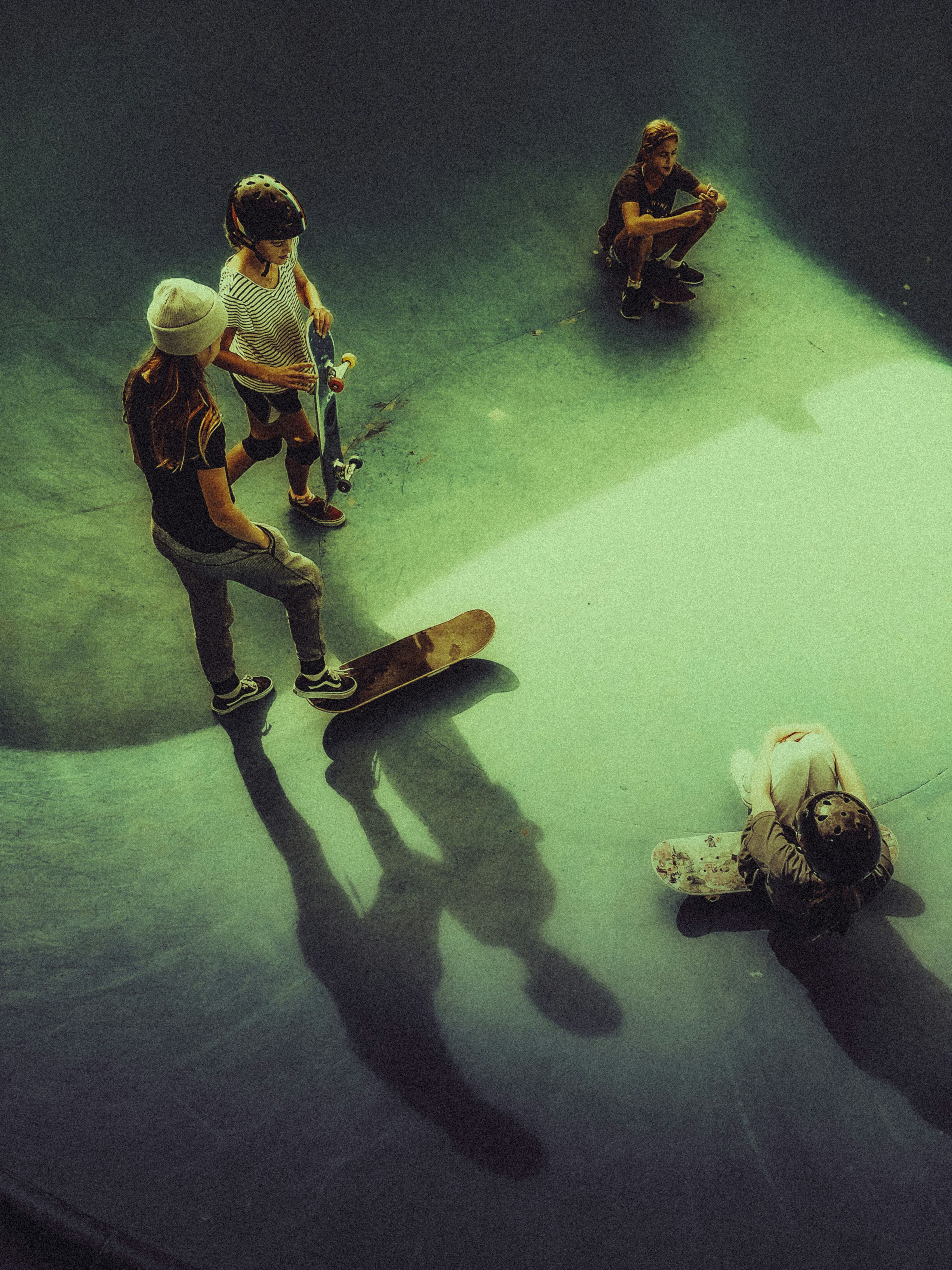 Skaters hang out in a skate park's empty bowl.