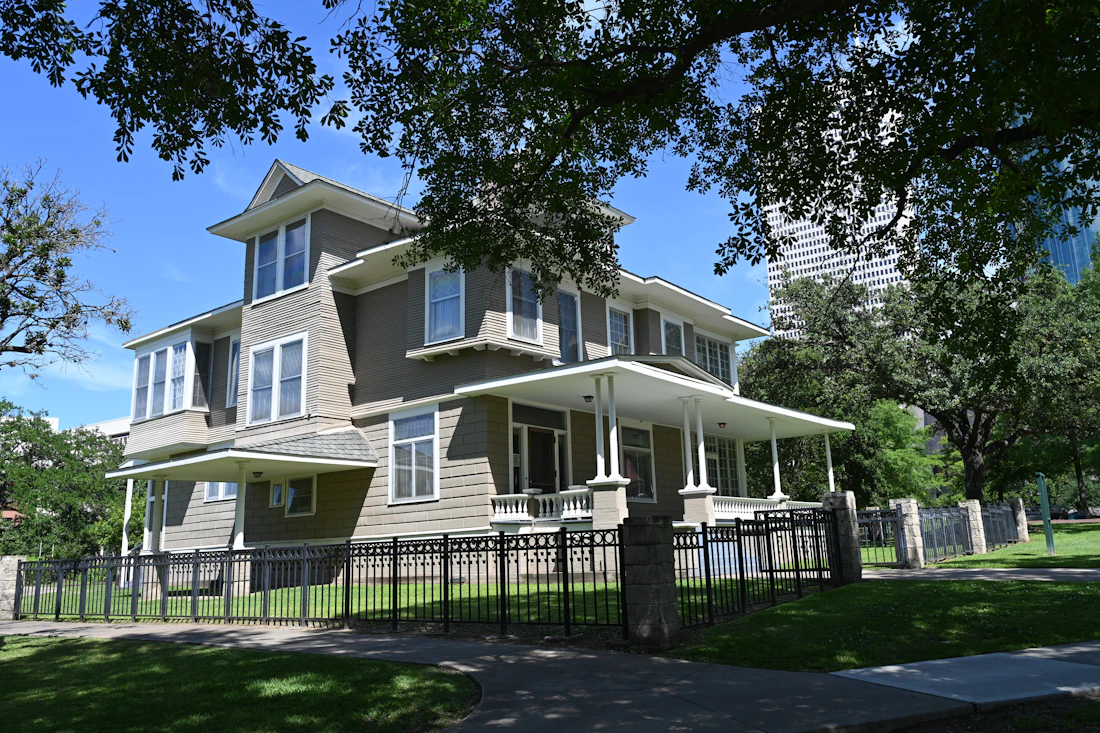 Two-story house behind a black ornamental metal fence