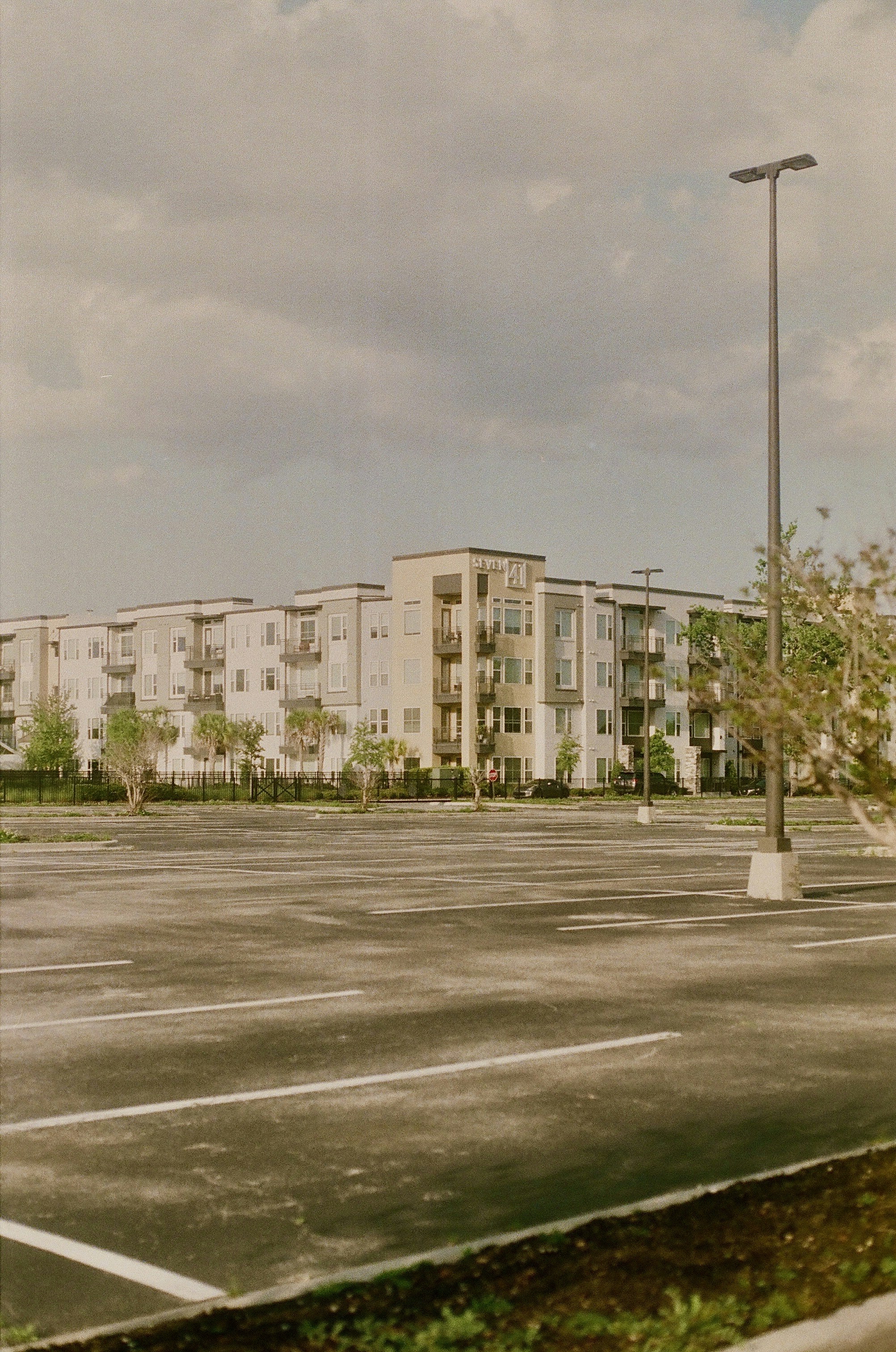 Apartment building with a large, empty parking lot.