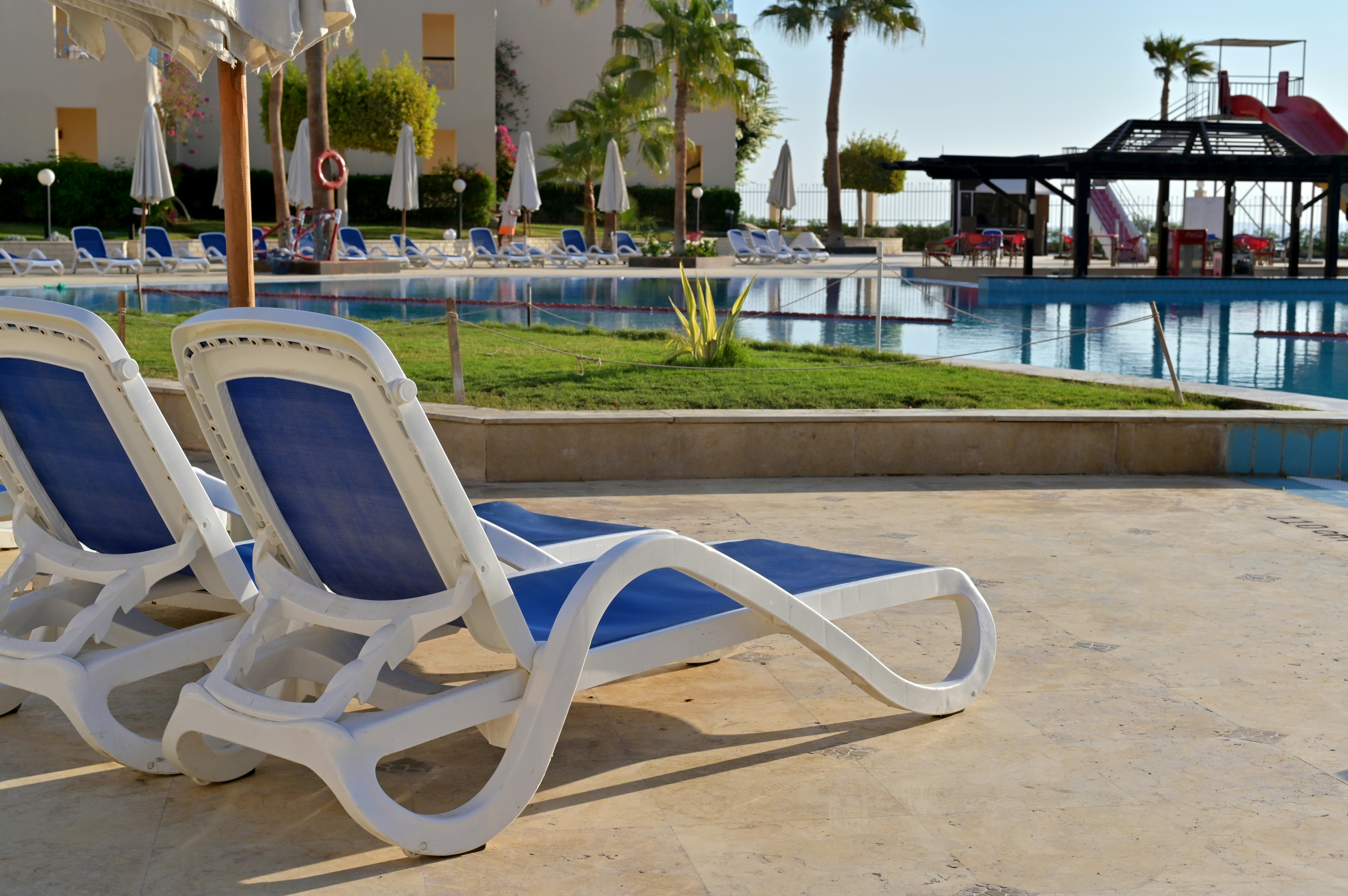 Lounge chairs sit by a pool on a sunny day.