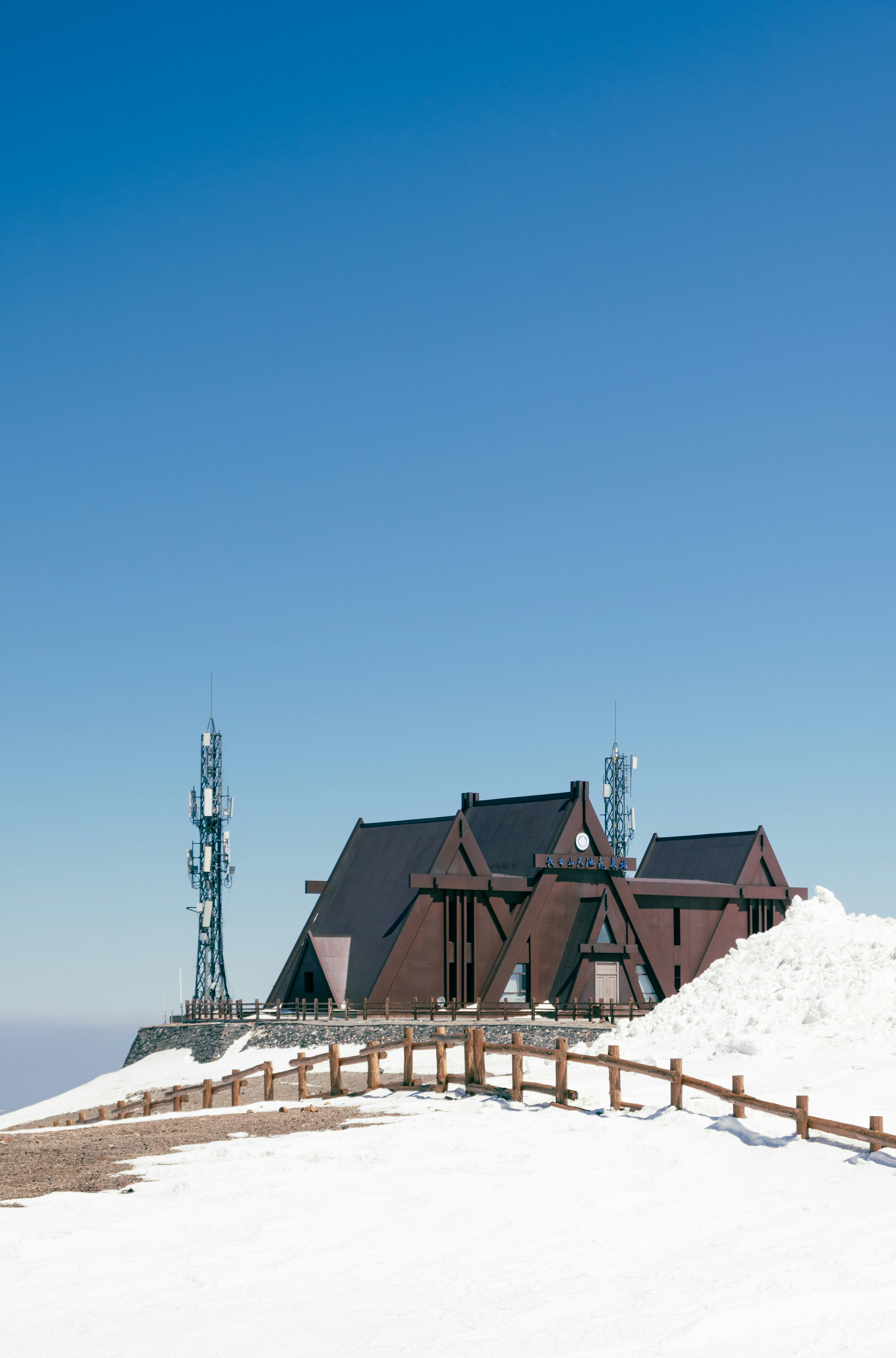 A wooden building sits atop a snow-covered mountain.