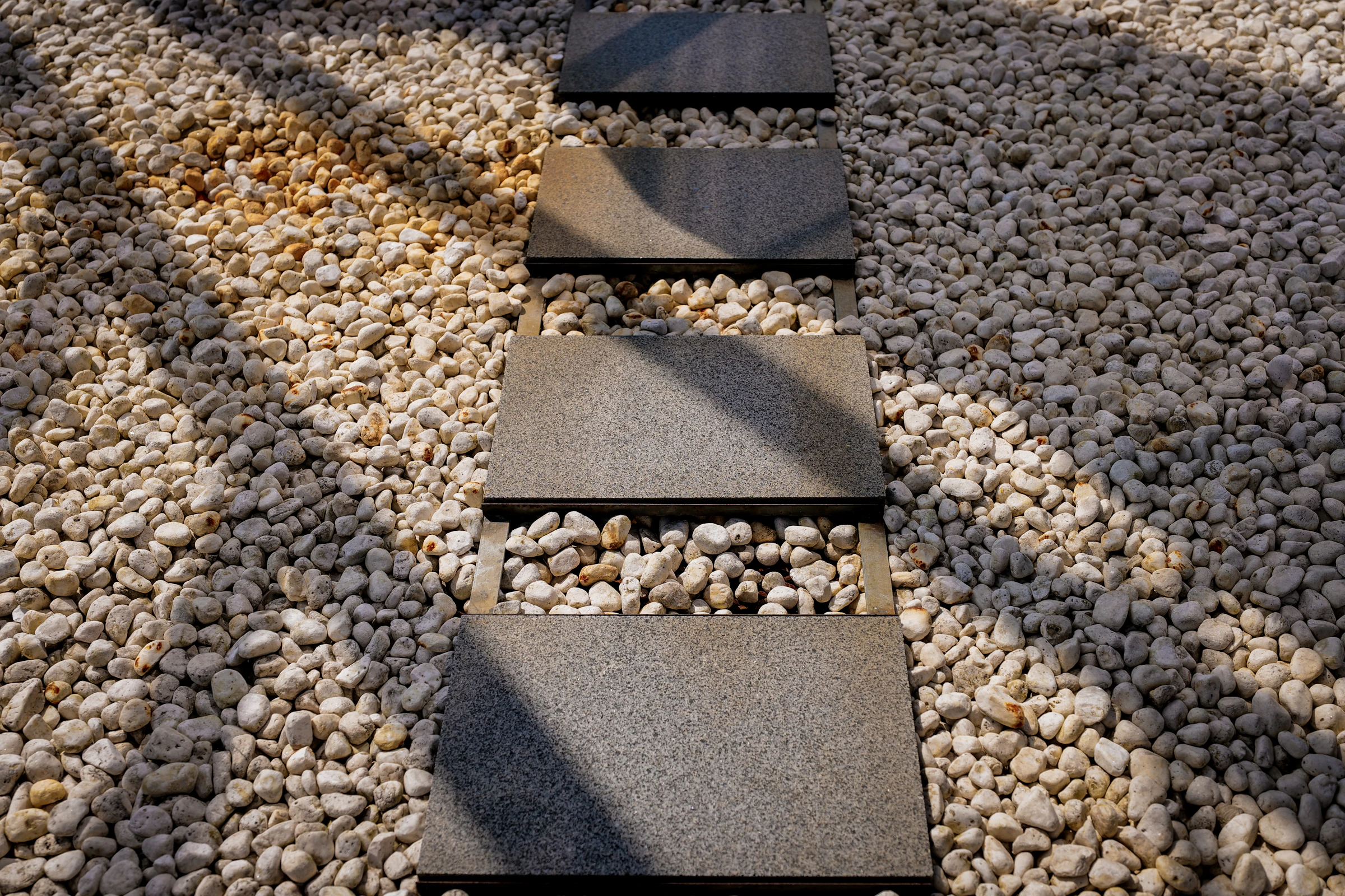 Stone pavers forming a pathway through pebbles