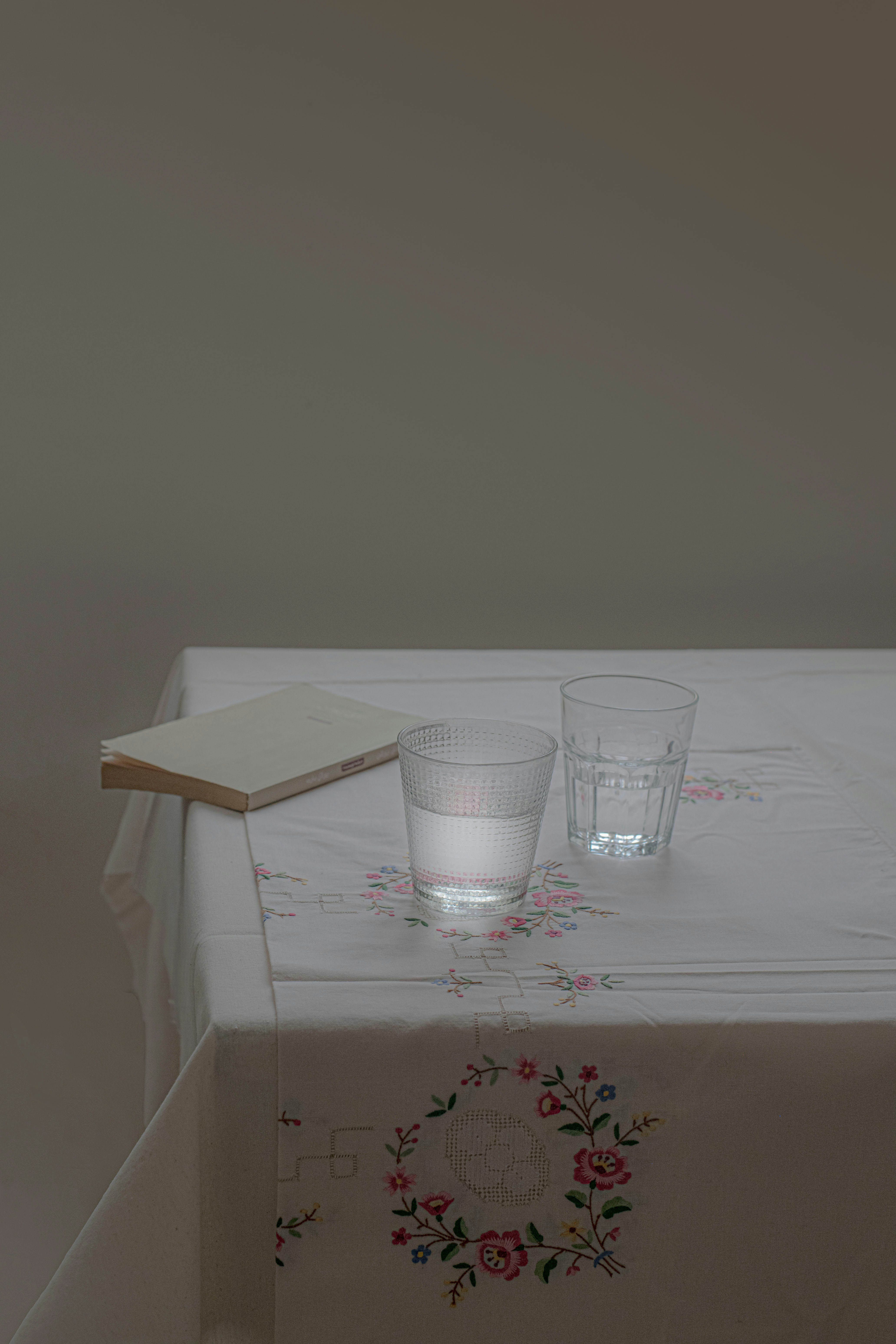 A book and two glasses sit on a table.