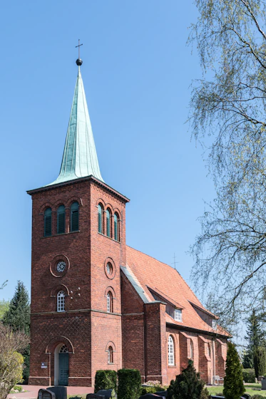 A red brick church with a green spire.