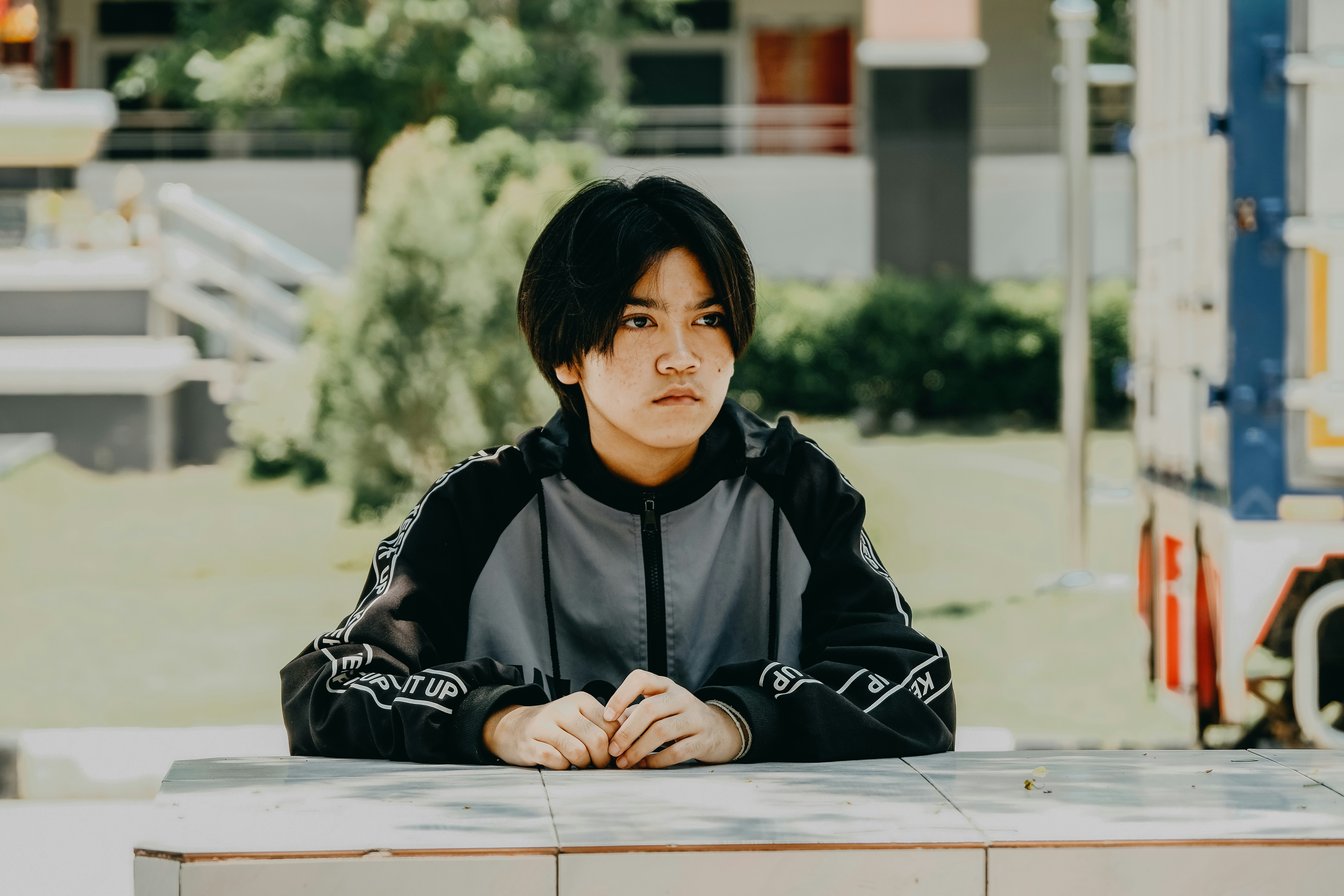 Young person sits thoughtfully outside.