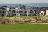 Suburban homes line a grassy area with benches.