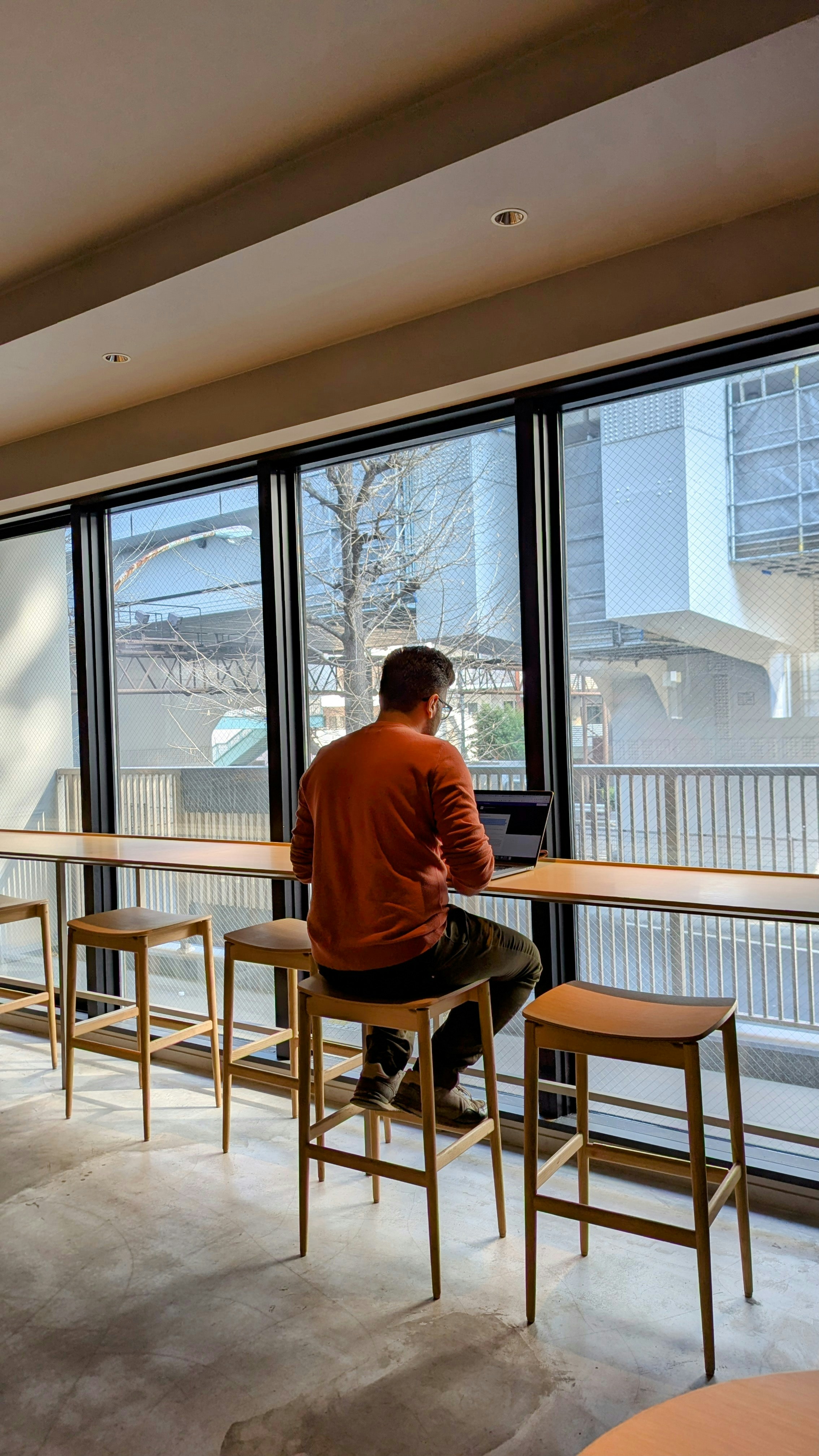 A man works on a laptop by a window.