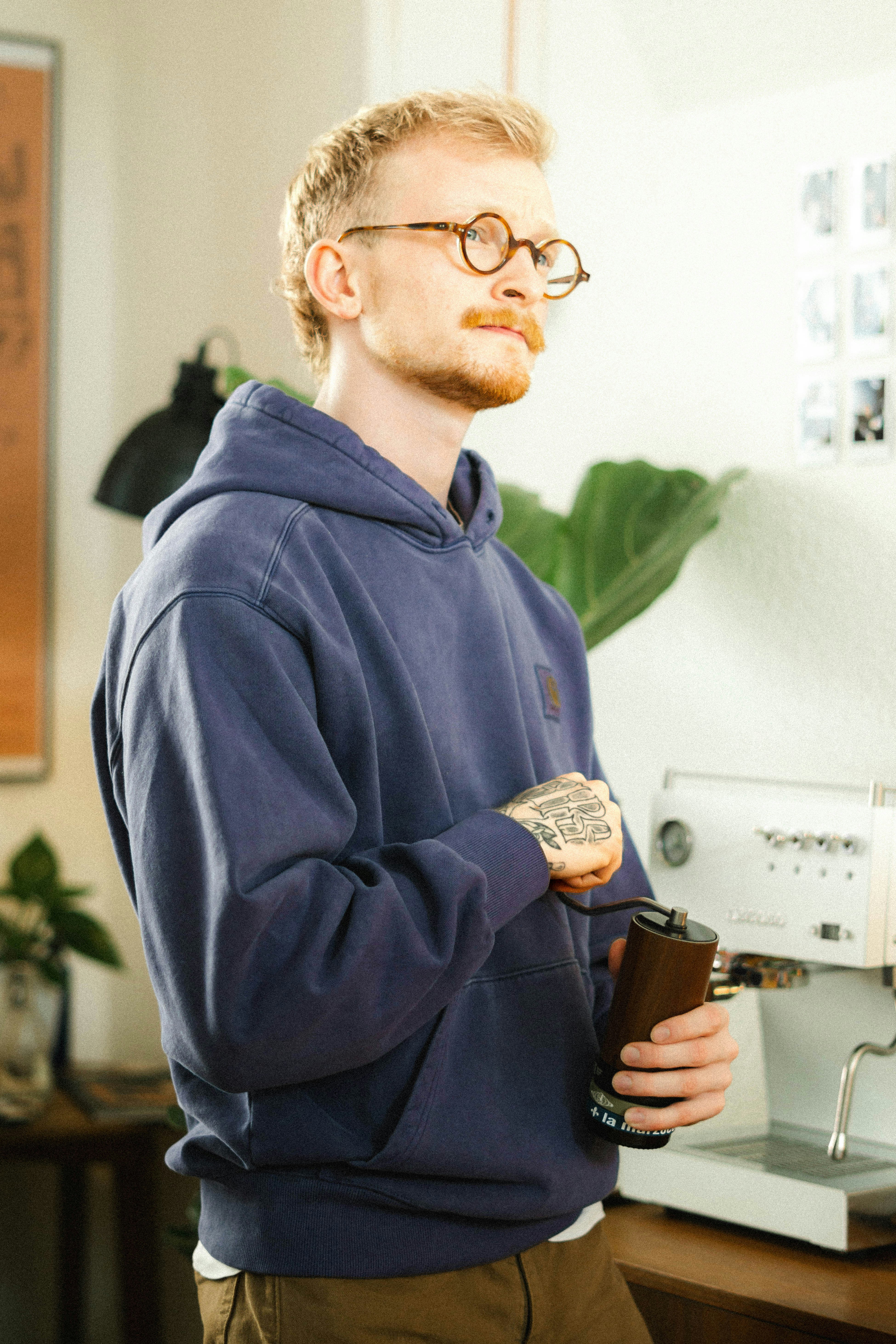 A man grinds coffee beans while looking away.