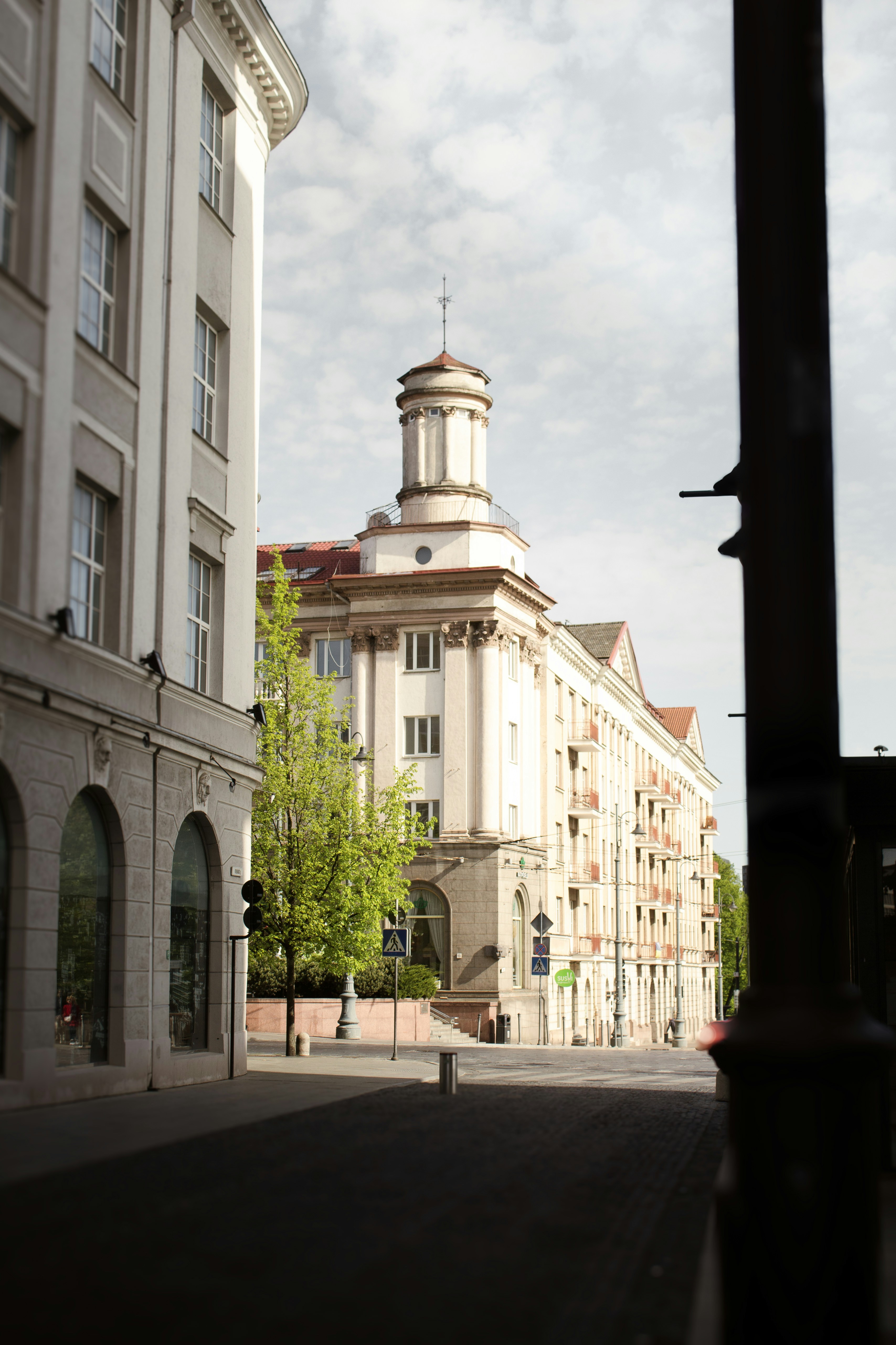 Buildings line a street beneath a cloudy sky.