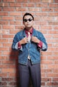 Man in vintage attire poses against a brick wall.