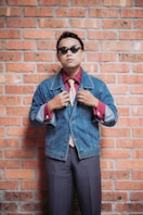 Man in vintage attire poses against a brick wall.