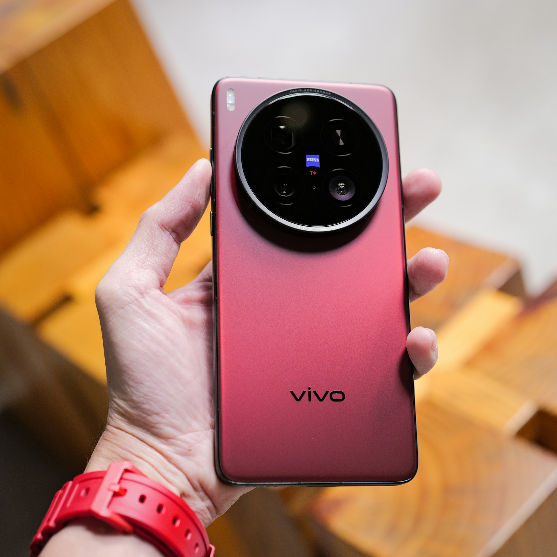 A person is holding a red vivo smartphone.