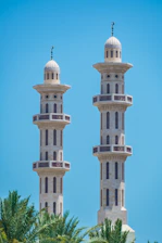 Two tall minarets stand against a blue sky.