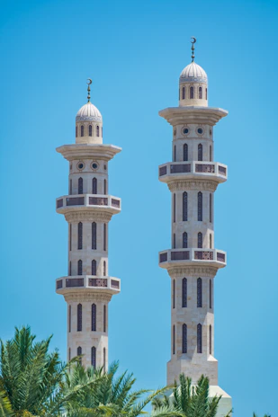 Two tall minarets stand against a blue sky.