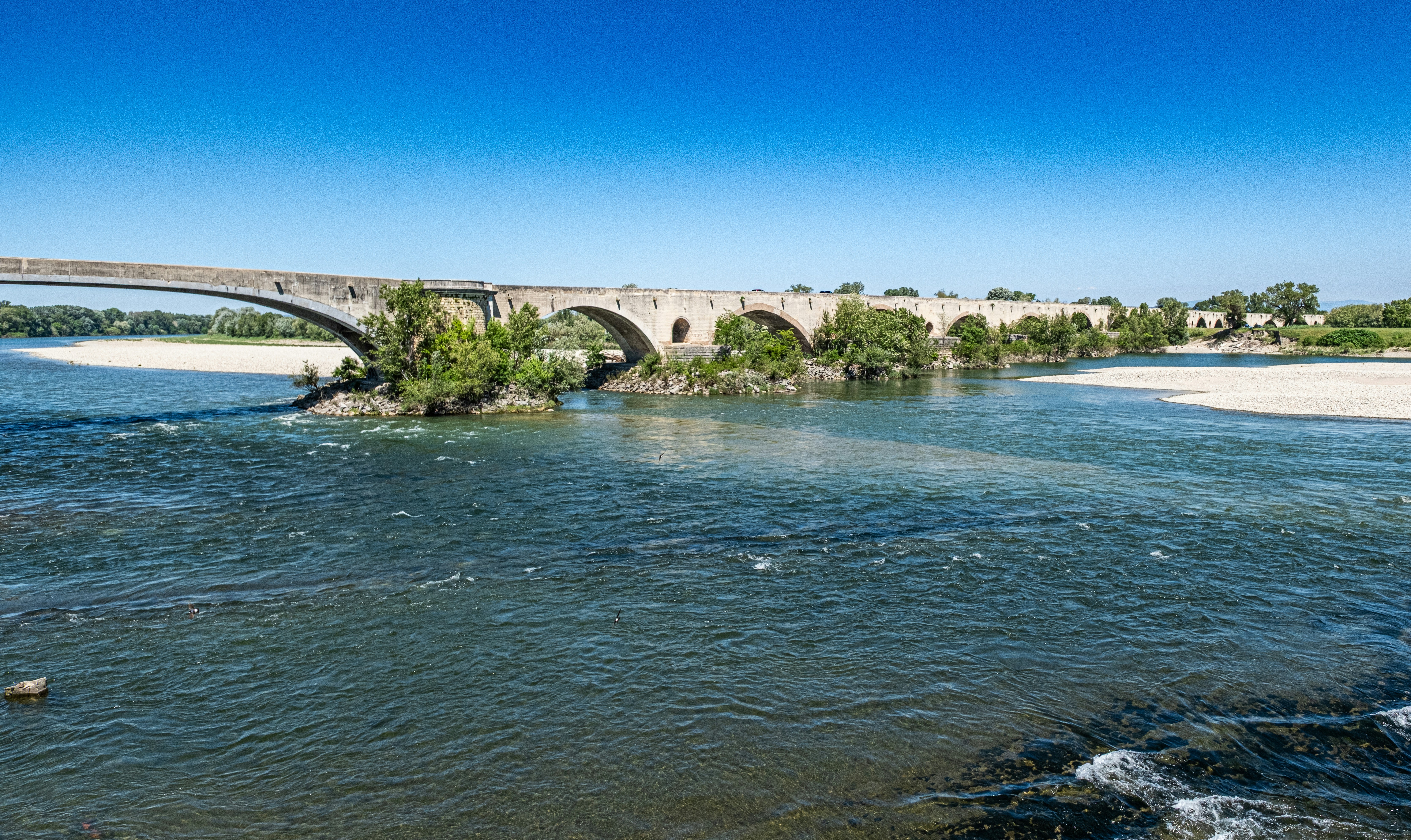 An old stone bridge spans a flowing river.