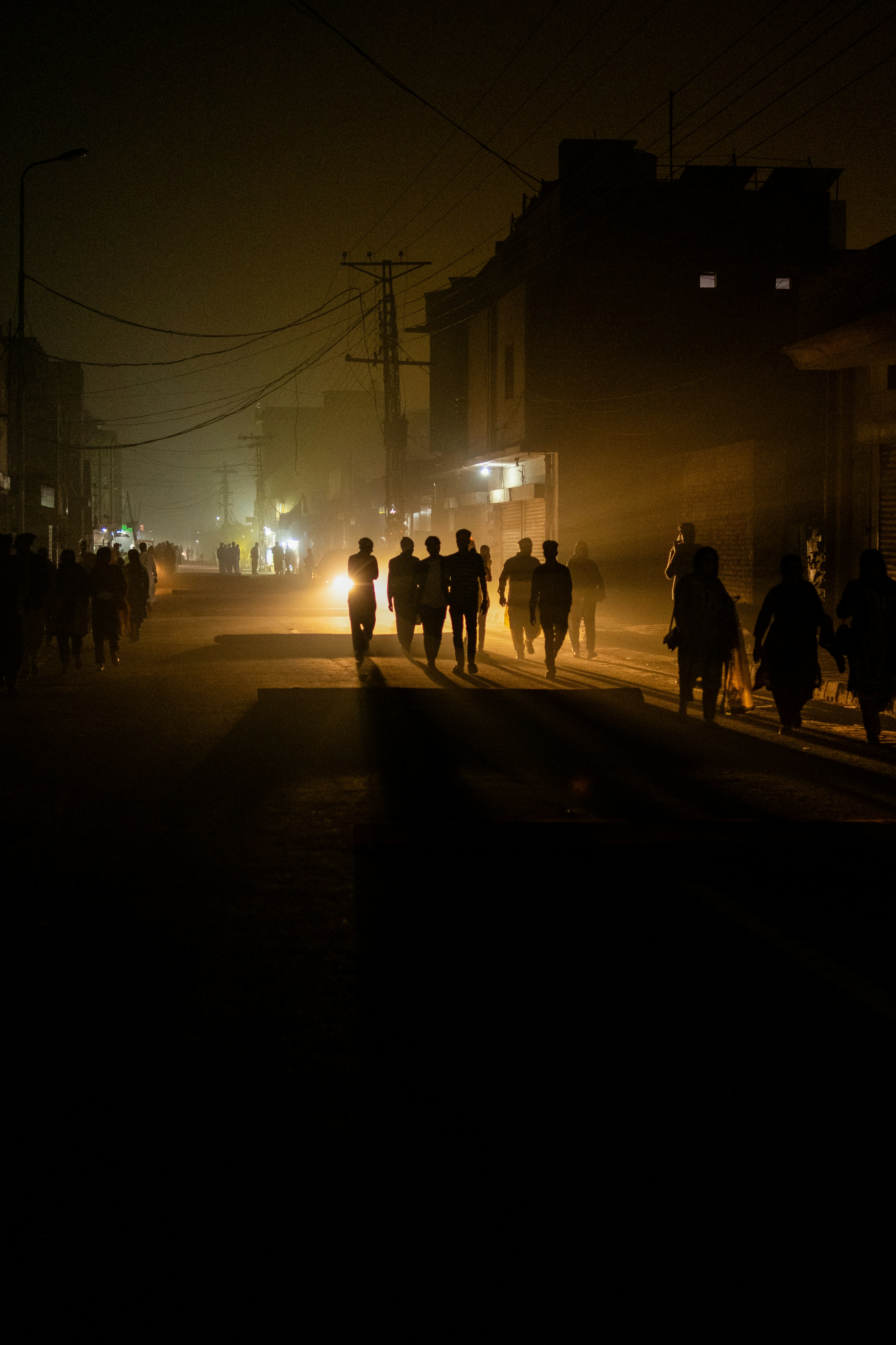 People walk down a street at night.
