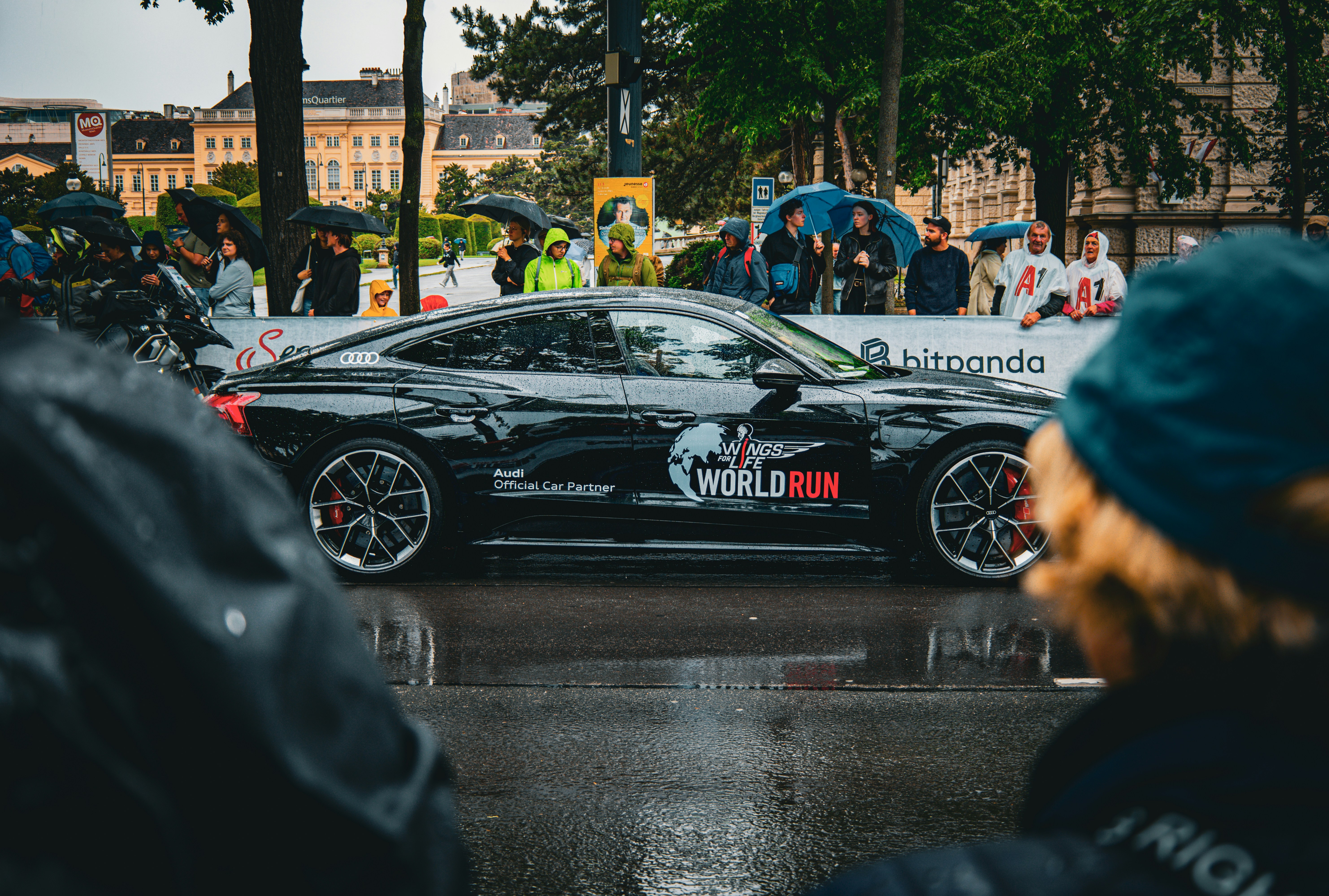 A black car is parked during a rainy event.